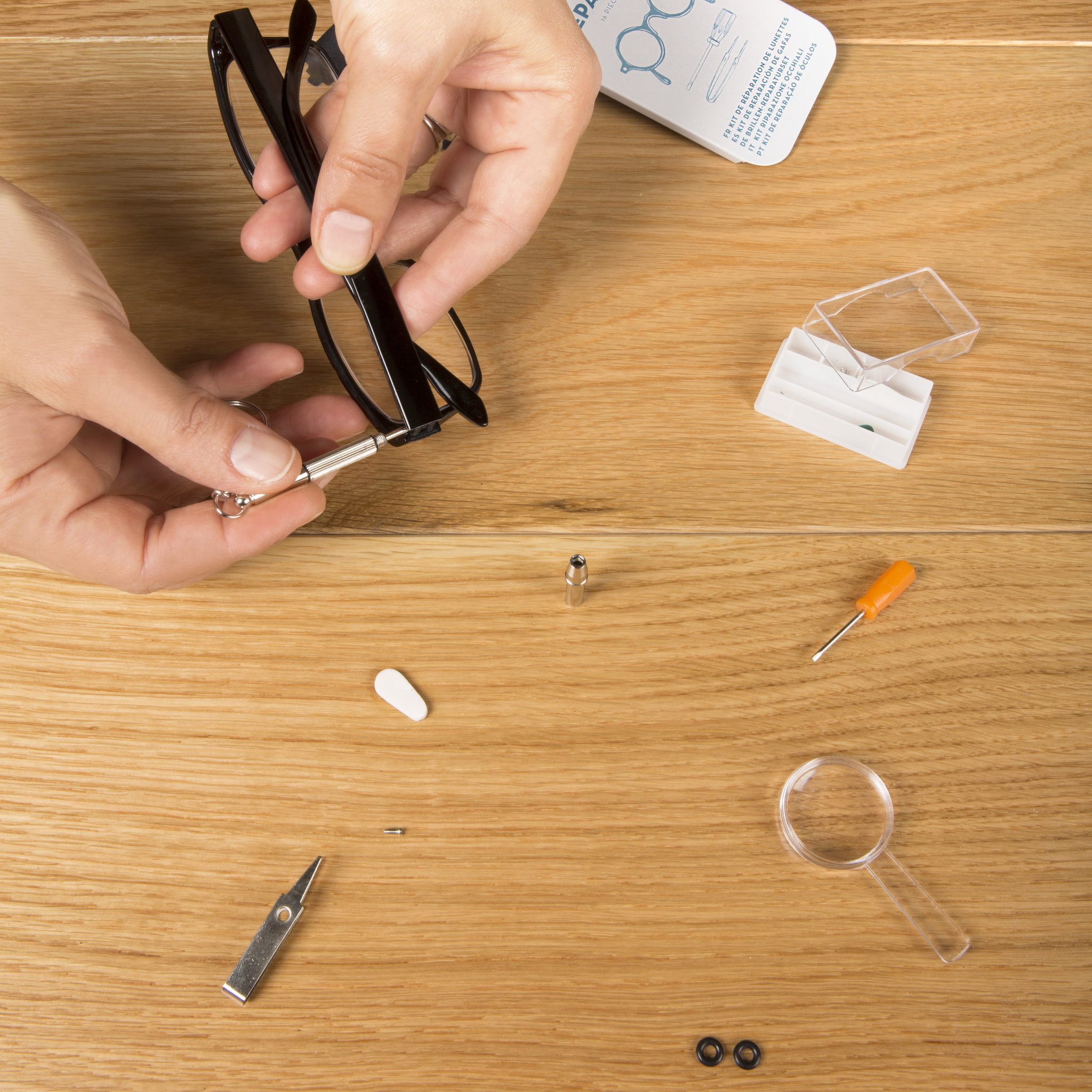 Hands tightening a glasses arm with the mini screwdriver