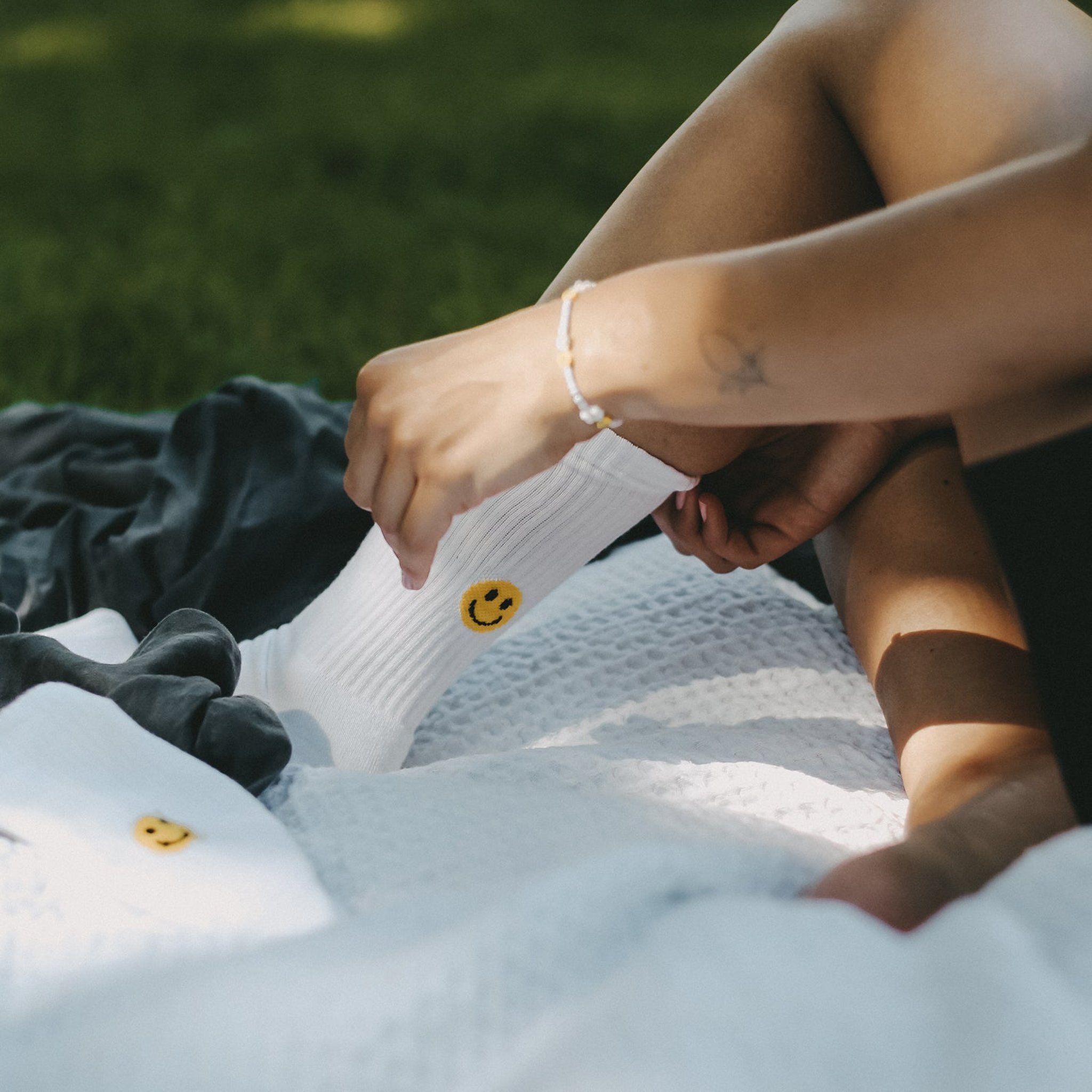 Socke mit gelbem Smiley wird auf einer Picknickdecke angezogen