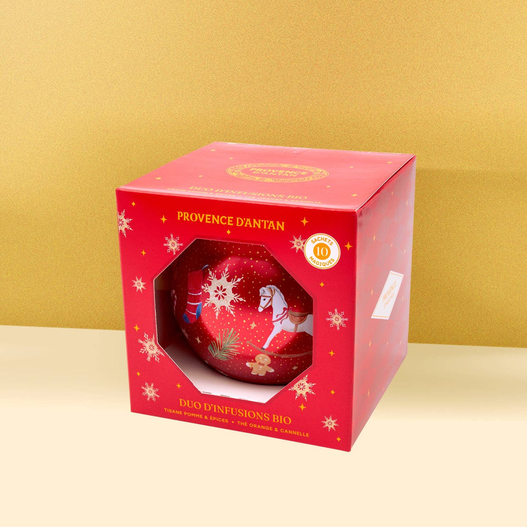 Rote Weihnachtskugel im Geschenkkarton mit Sichtfenster vor goldenem Hintergrund