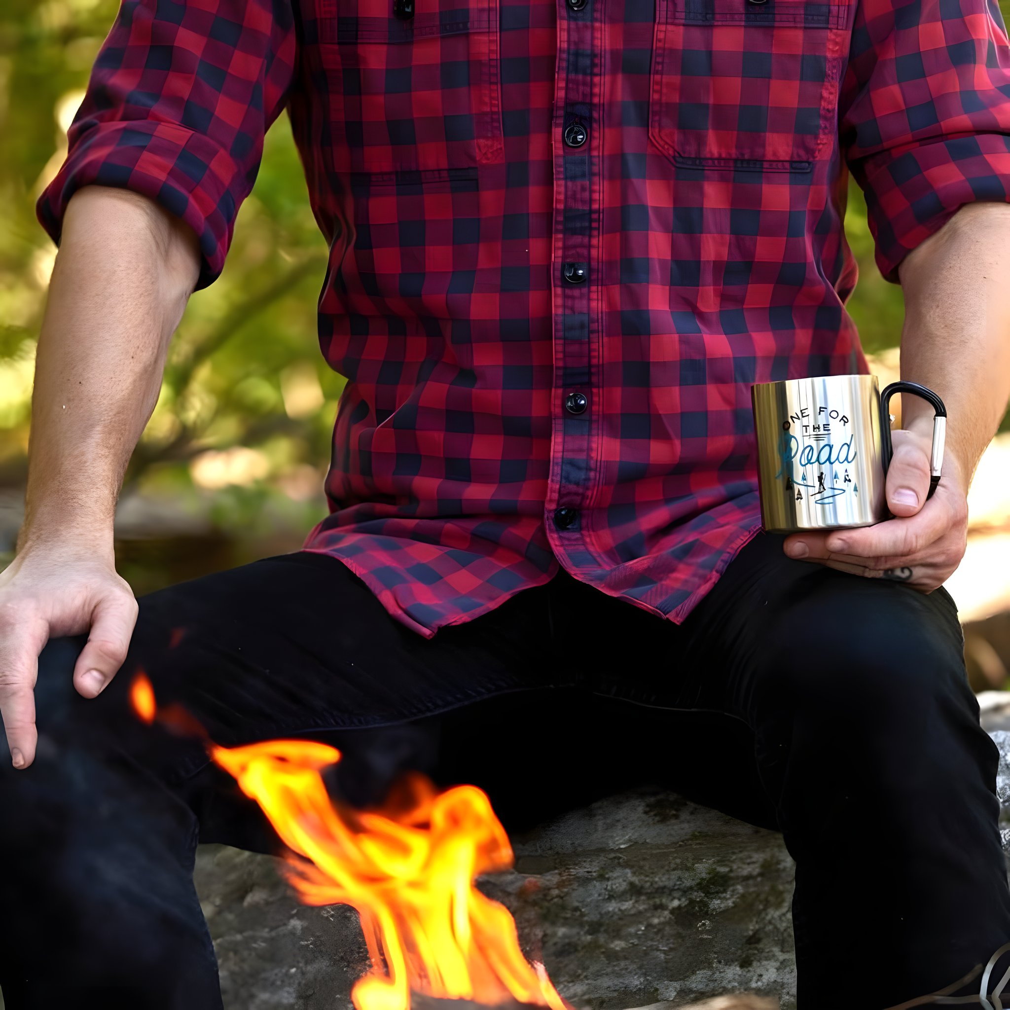Mann im rot karierten Hemd sitzt am Lagerfeuer und hält die Karabinertasse in der Hand