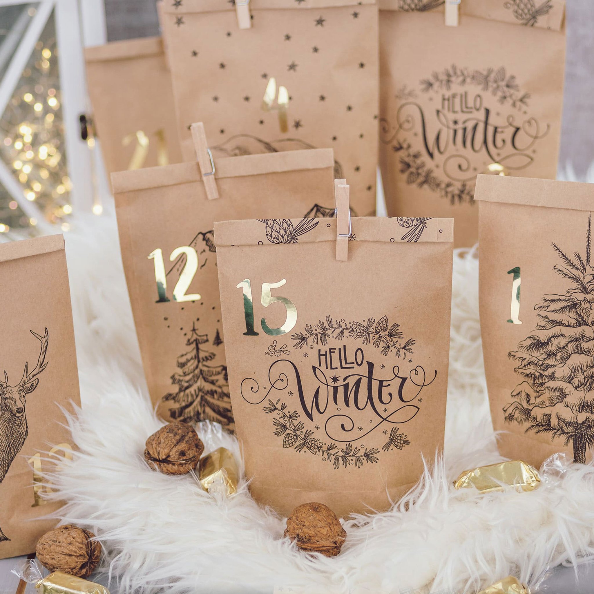 Tüten 12 und 15 mit Hello-Winter-Schriftzug und Hirsch, dazu Walnüsse und Goldbonbons auf Fell