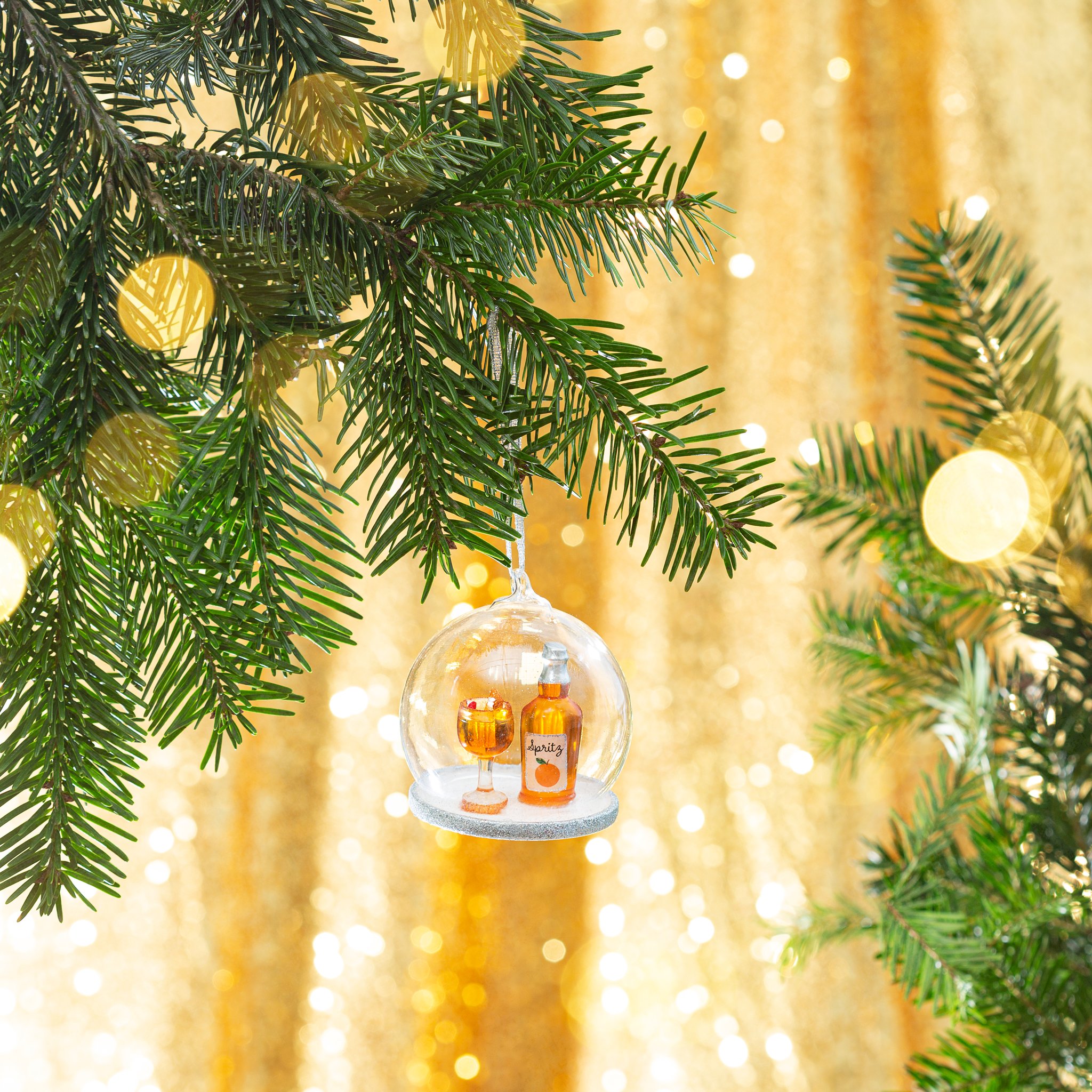 Spritz-Cocktail-Weihnachtskugel hängend im Weihnachtsbaum mit goldenem Bokeh
