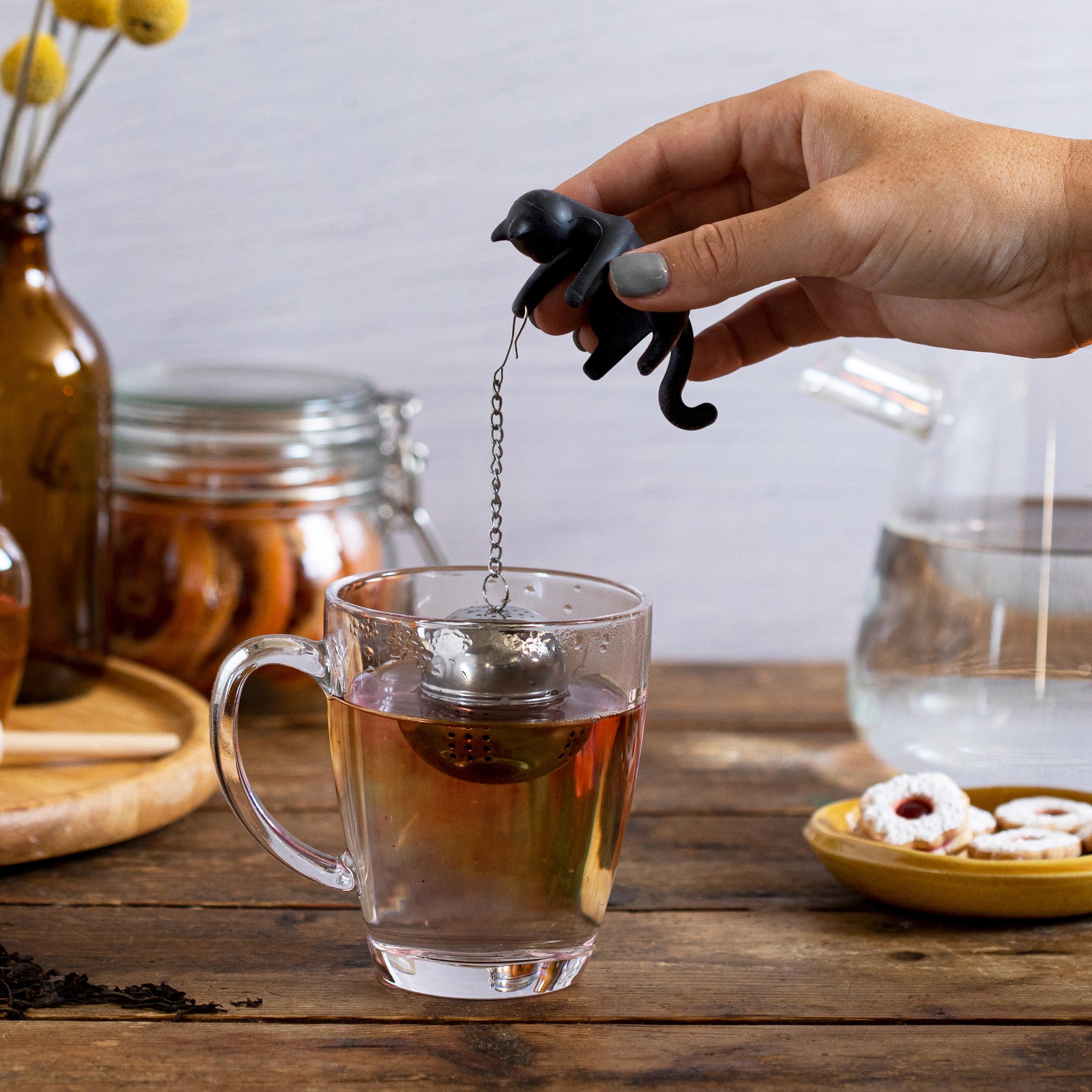 Cattea tea infuser being lifted by chain from glass mug