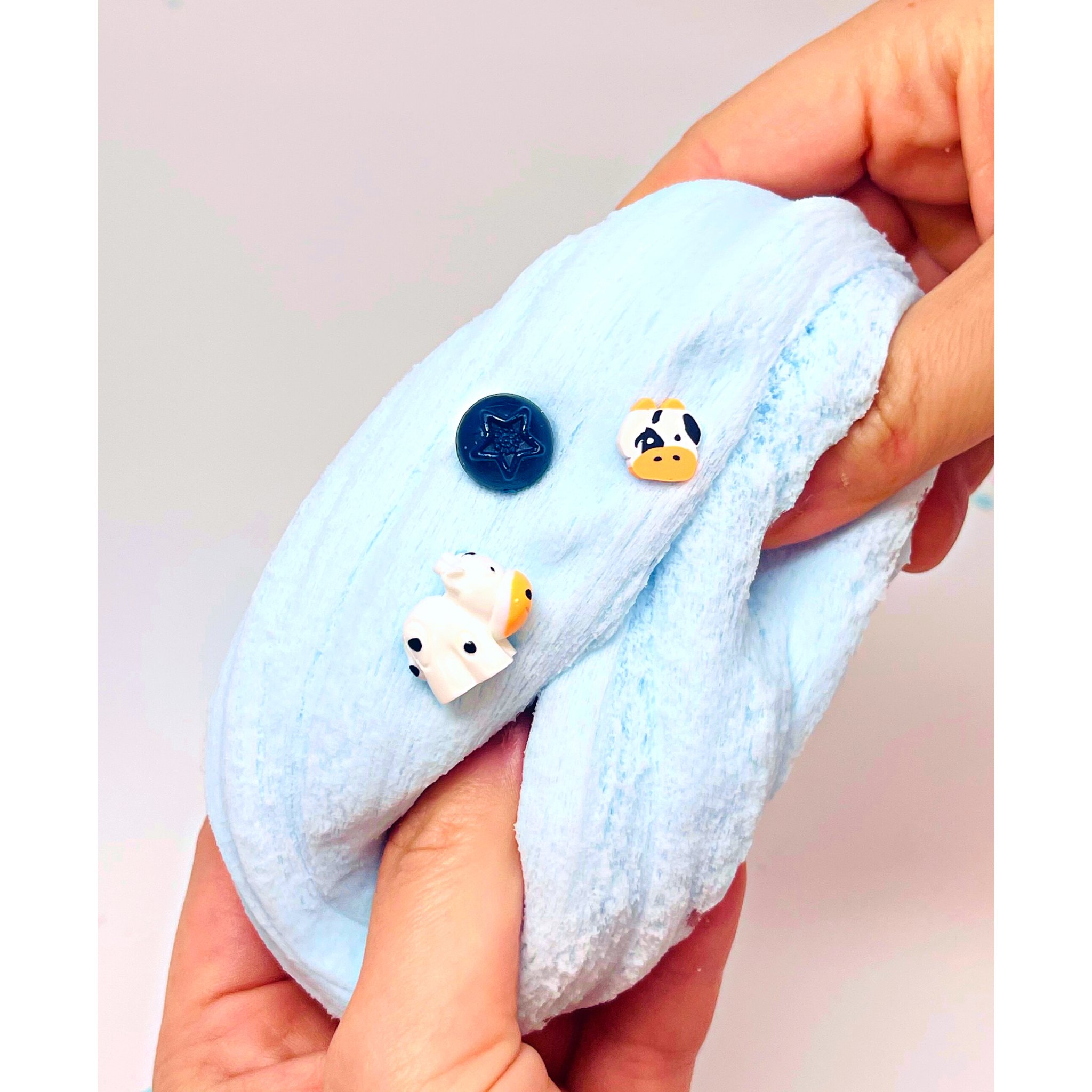 Hände ziehen den fluffigen Blueberry Cow Cloud-Slime auseinander