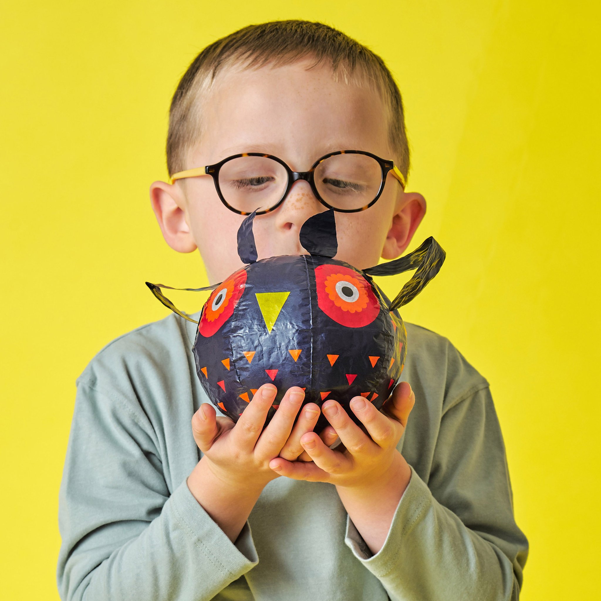 Junge mit Brille hält den Eulen-Papierballon in den Händen