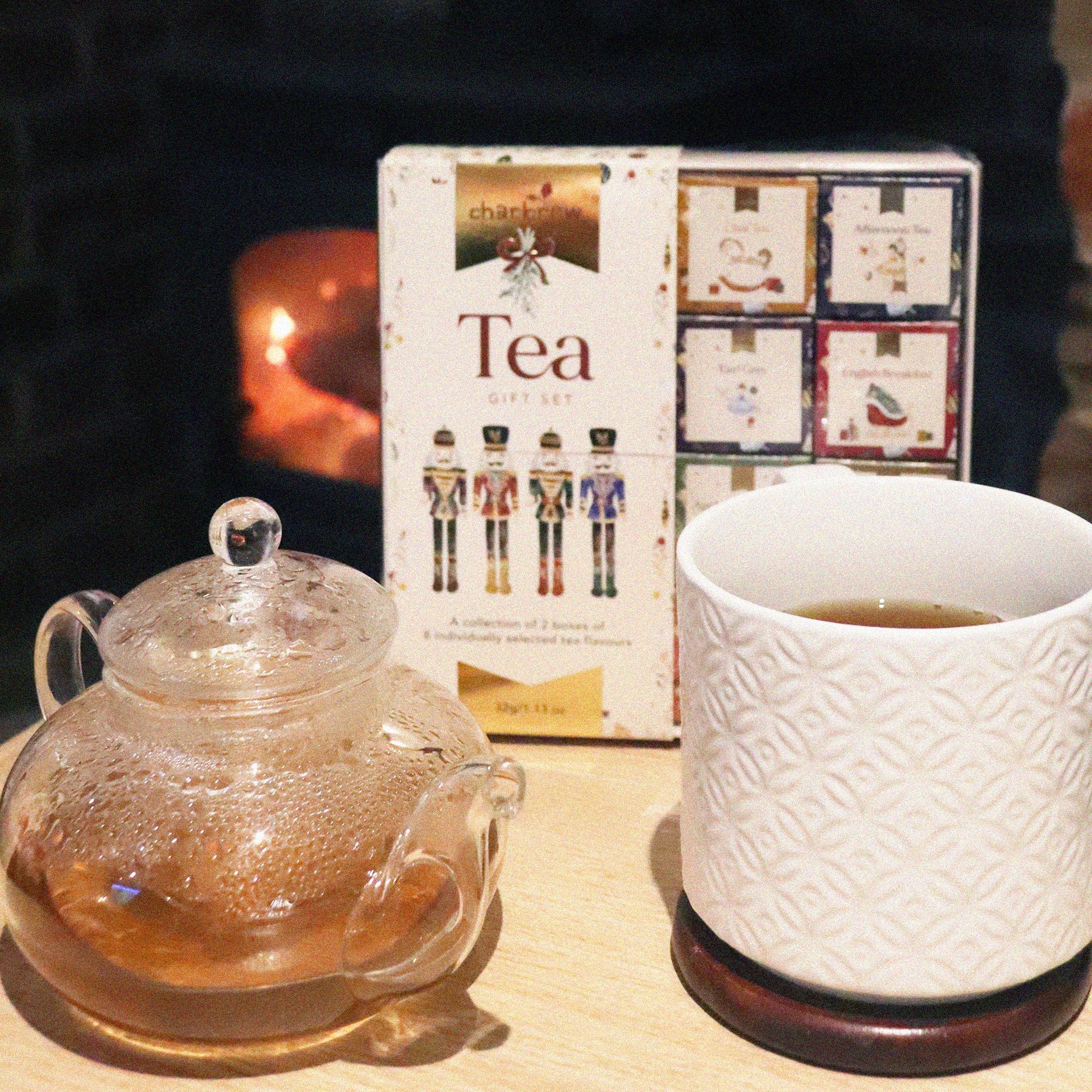 Nutcracker tea set on a table with glass teapot and mug in front of a fireplace