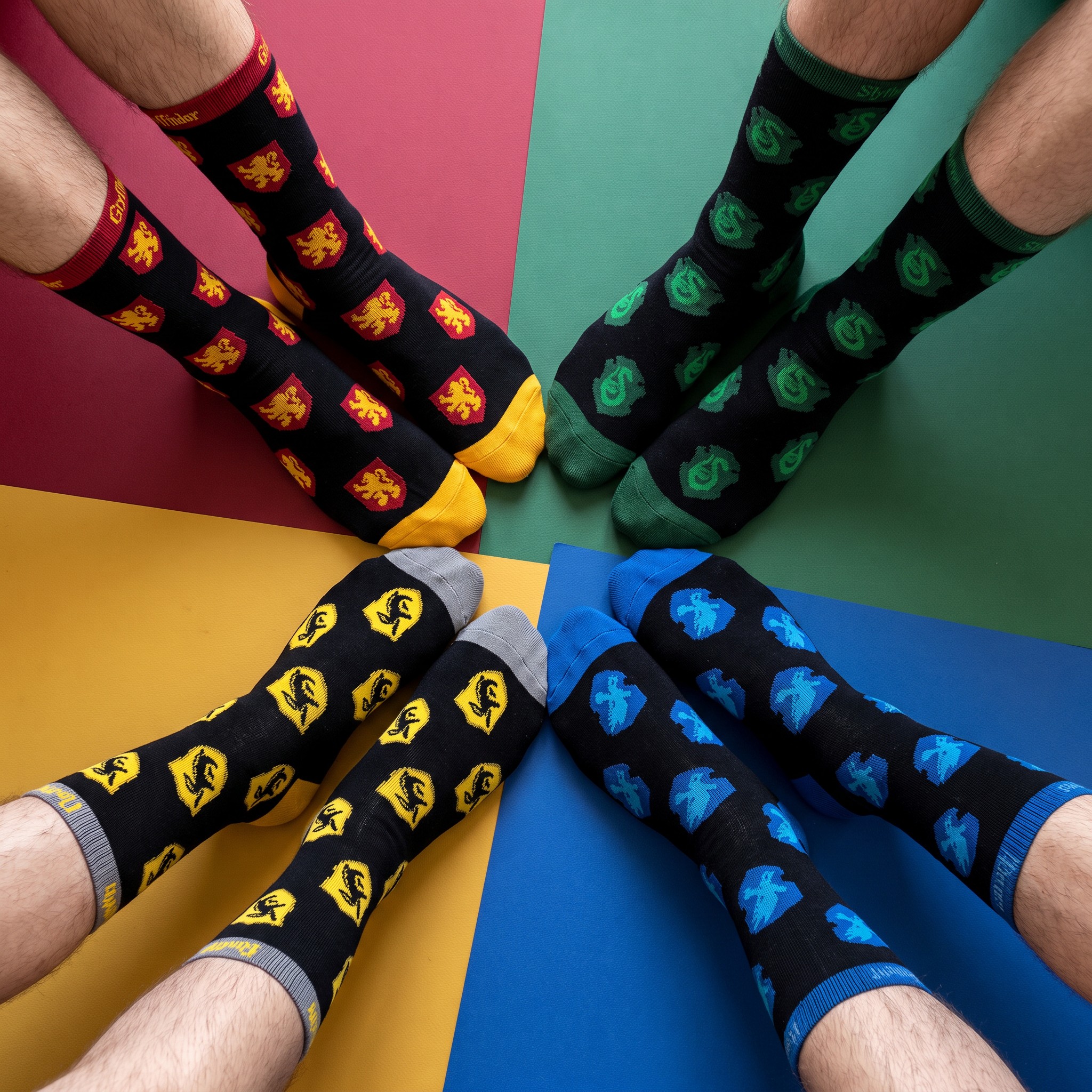 Quatre paires de chaussettes hautes Harry Potter aux couleurs de Gryffondor, Serpentard, Poufsouffle et Serdaigle, portées en étoile