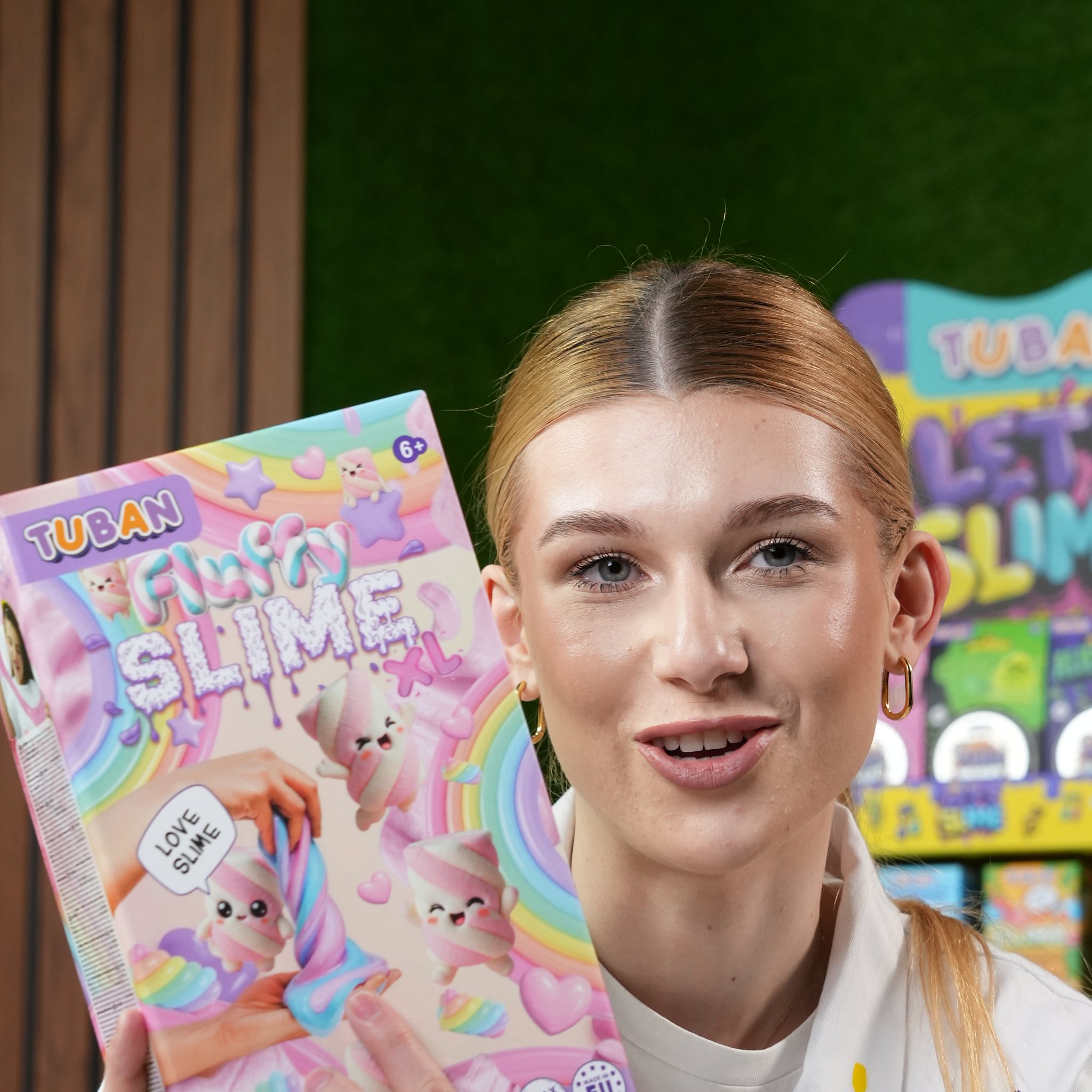 Frau im Kittel zeigt die Verpackung des Fluffy-Slime-Sets XL