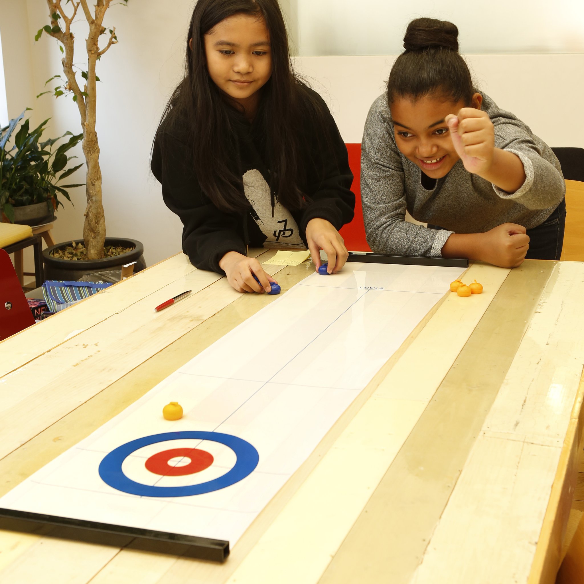 Curling da tavolo Kikkerland – due ragazze in gioco