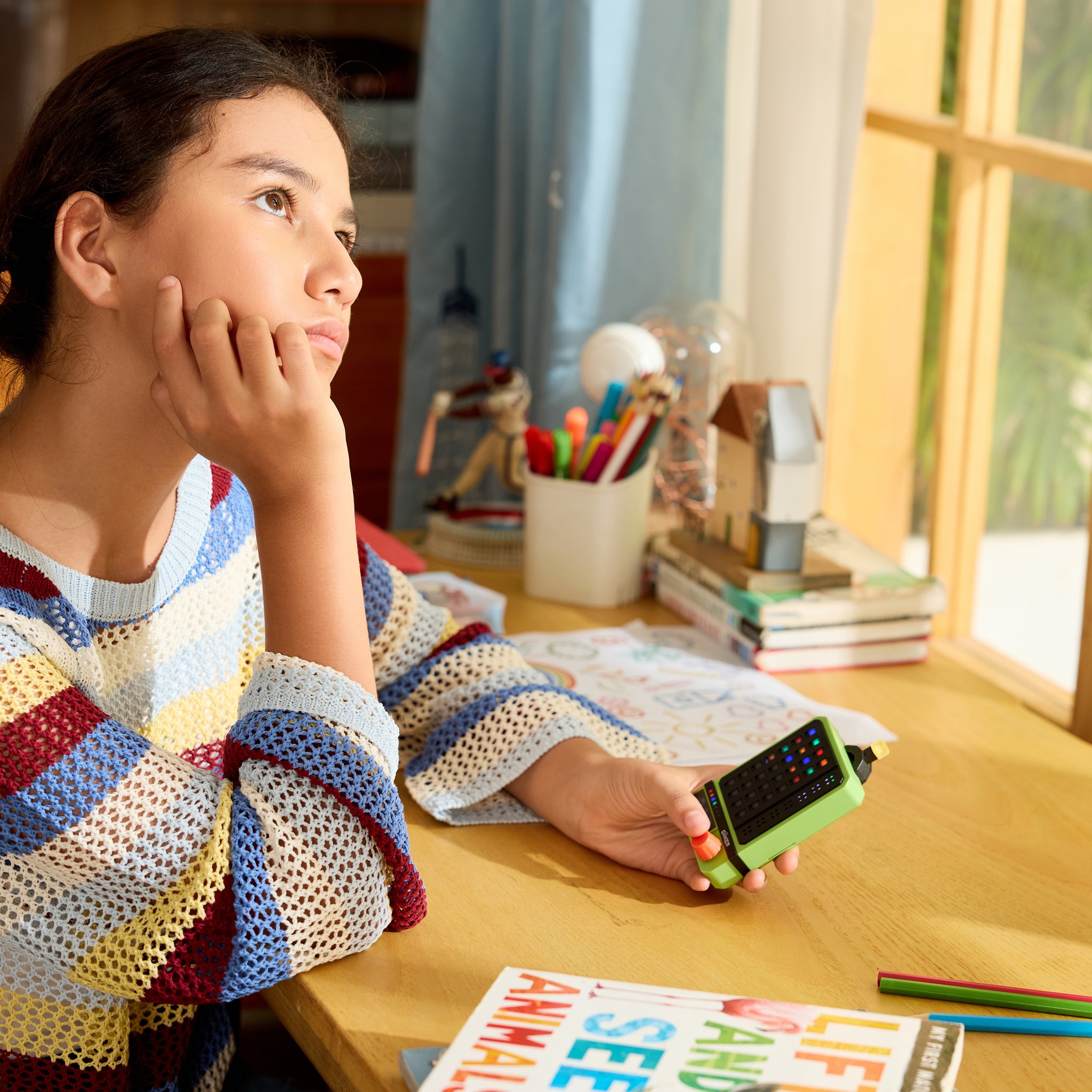 A girl sits at her desk, thinking hard about the colour code on her Super Decoder.