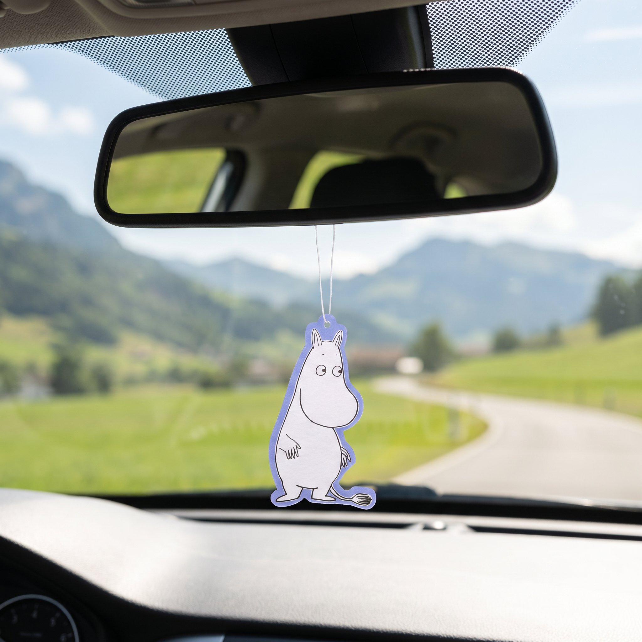 Moomin peach air freshener hanging from the rear-view mirror, country road and mountains outside