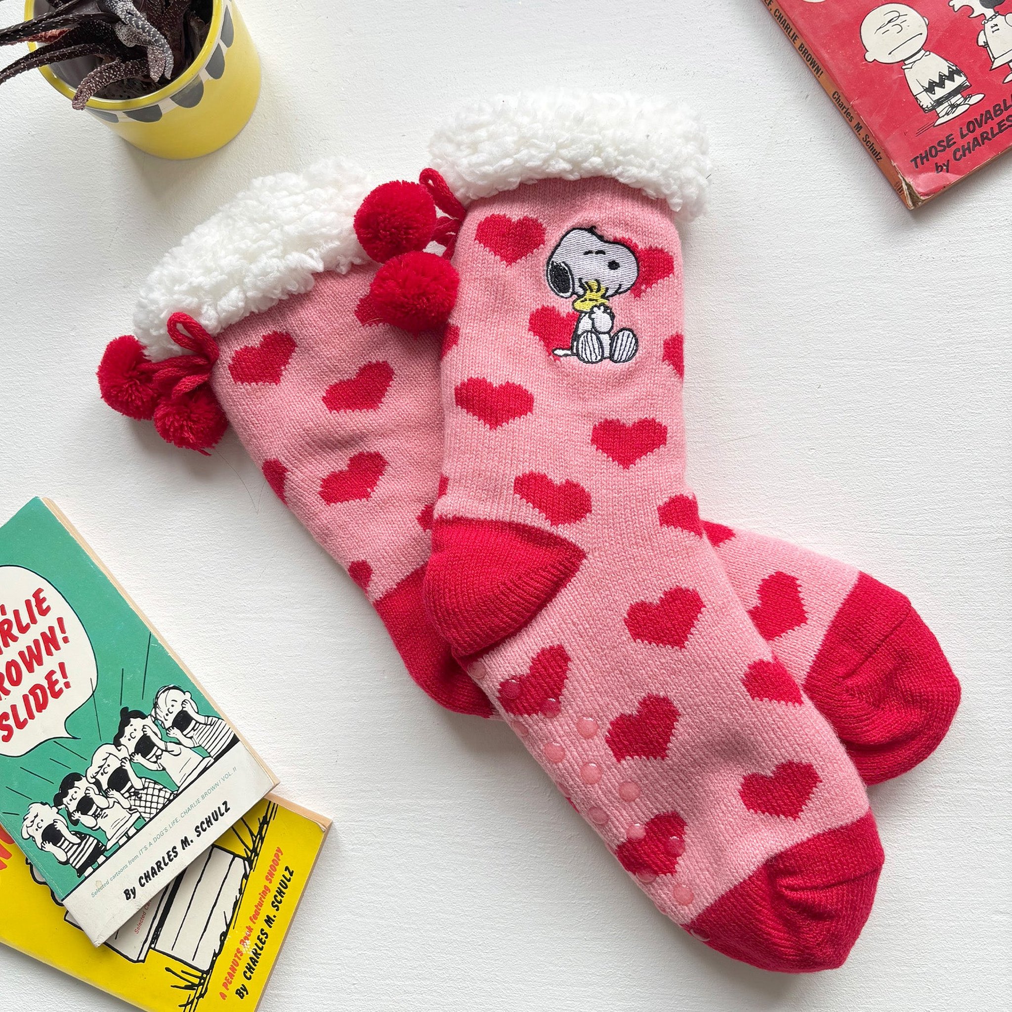 Kuschelsocken mit Snoopy, der Woodstock umarmt, auf weissem Tisch