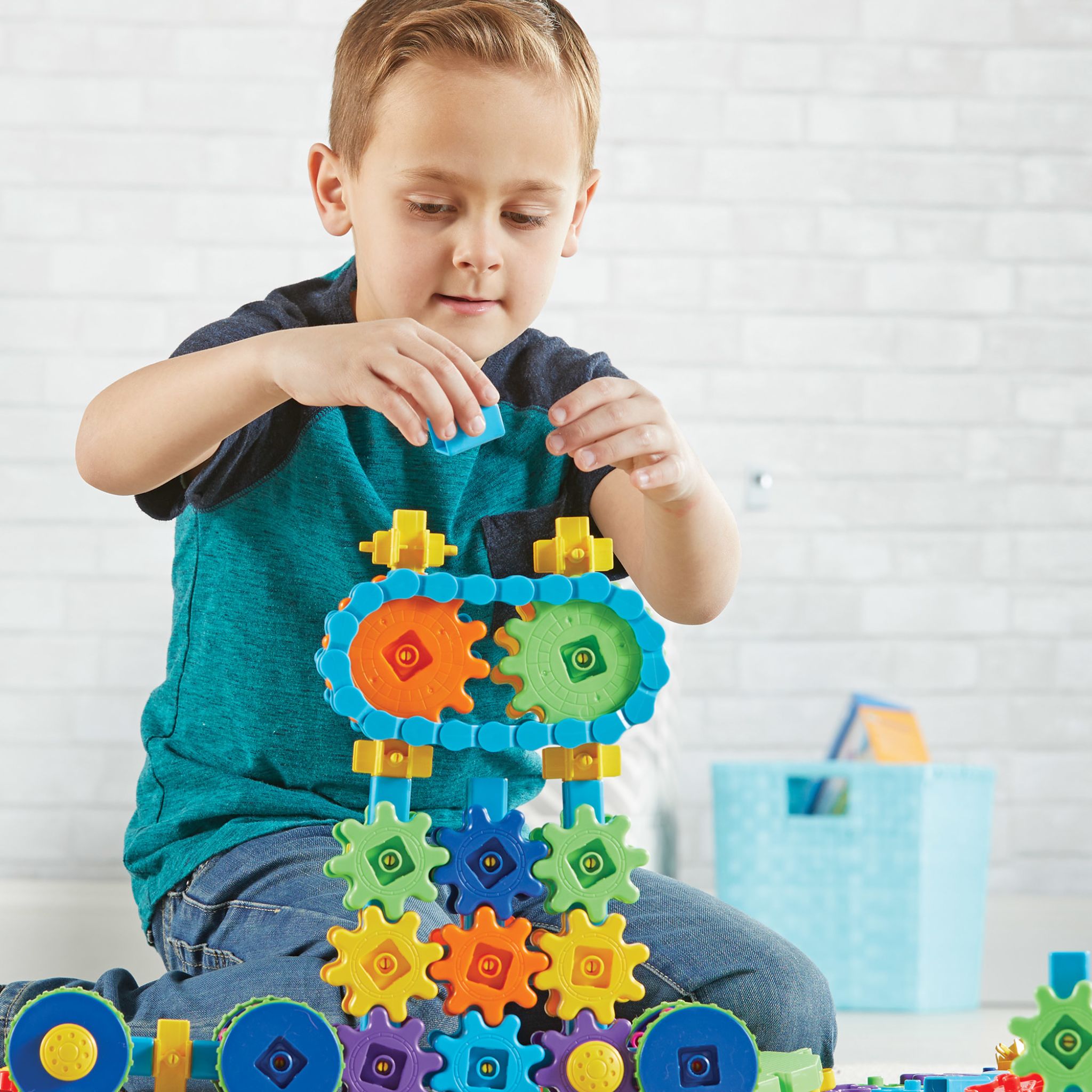 Junge baut mit dem Zahnrad-Bauset Gears! Mega Builds einen hohen Turm aus bunten Zahnrädern