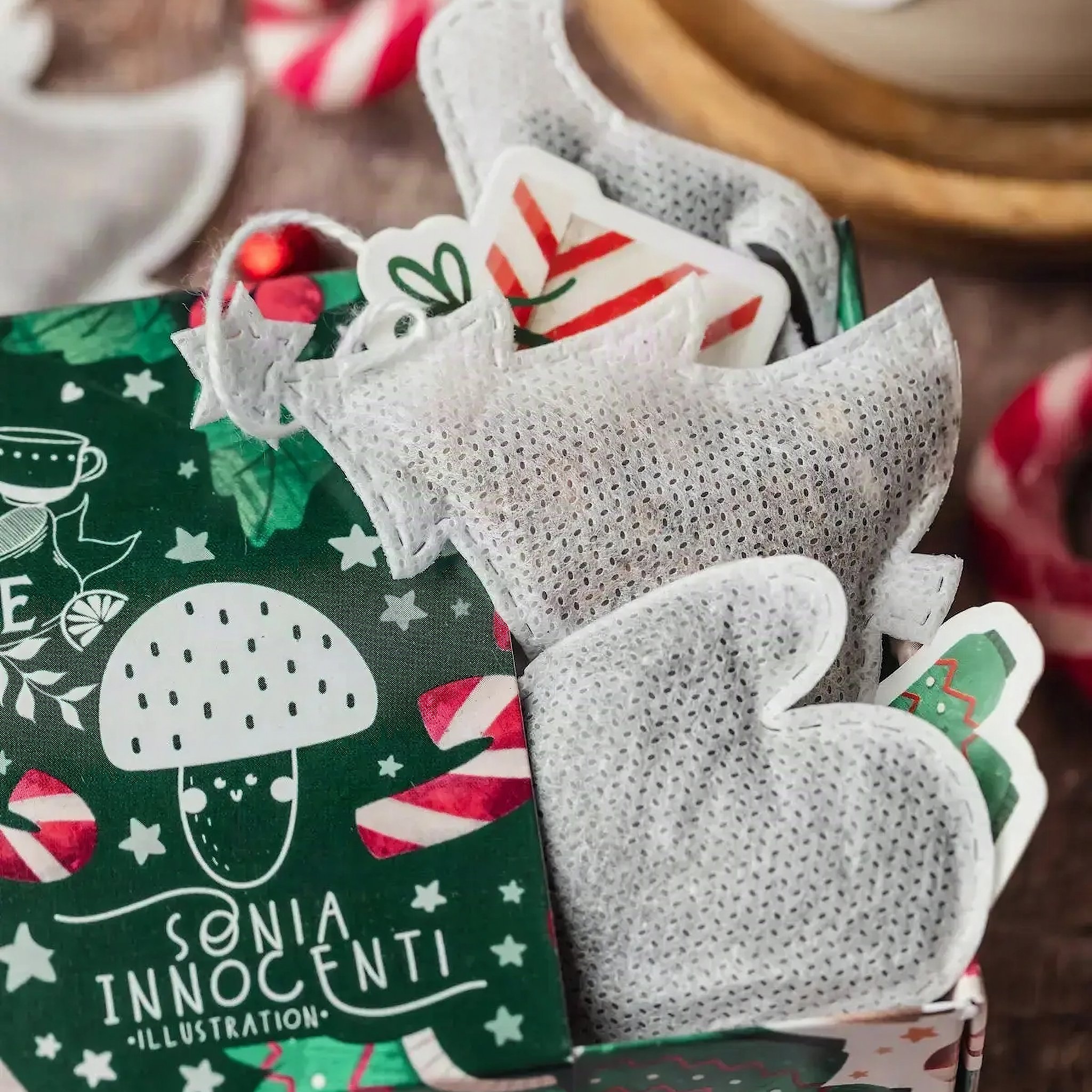 Cofanetto di Natale aperto con bustine a forma di muffola e di abete, illustrazione di Sonia Innocenti