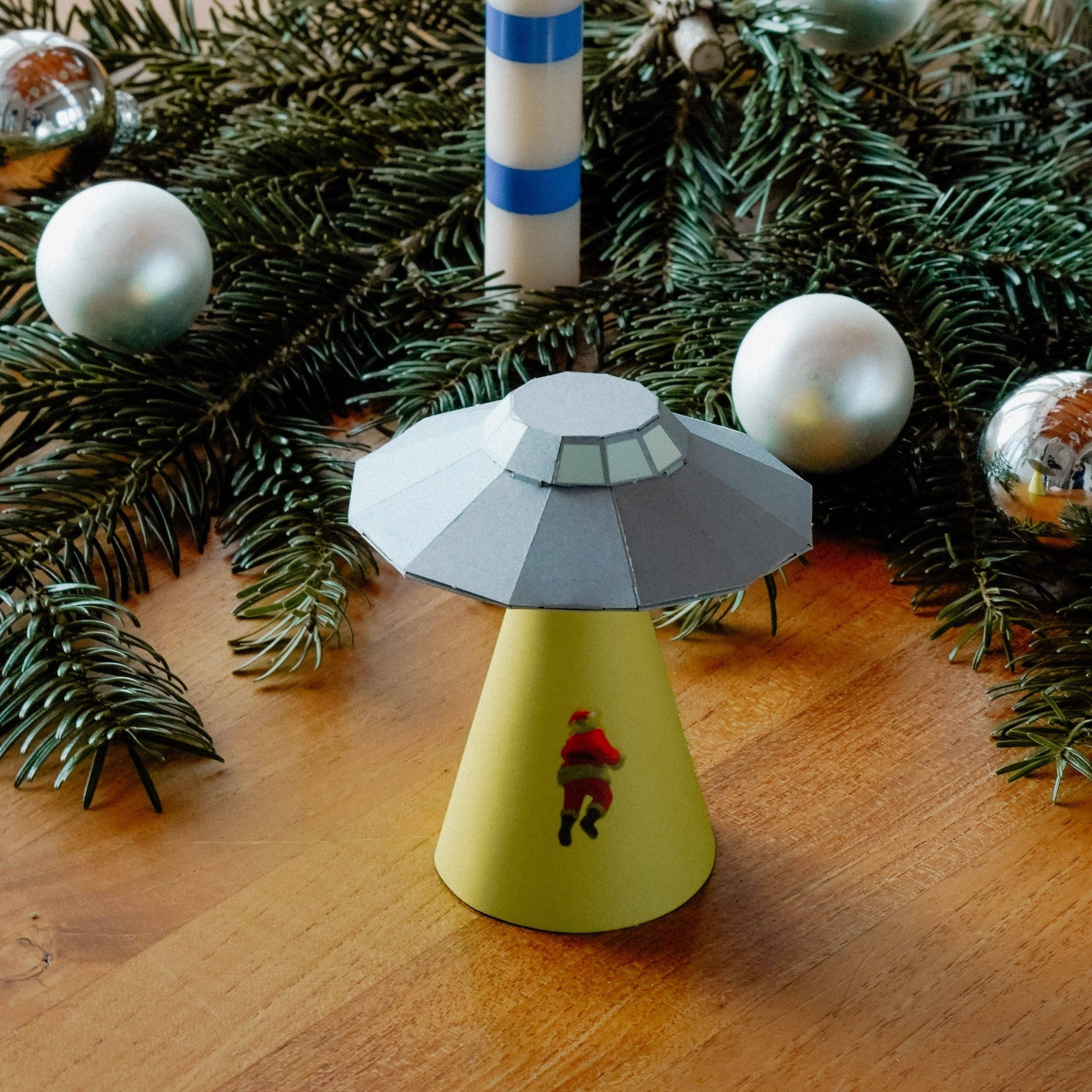Gefaltetes Papier-UFO mit Weihnachtsmann unter dem geschmückten Tannenbaum