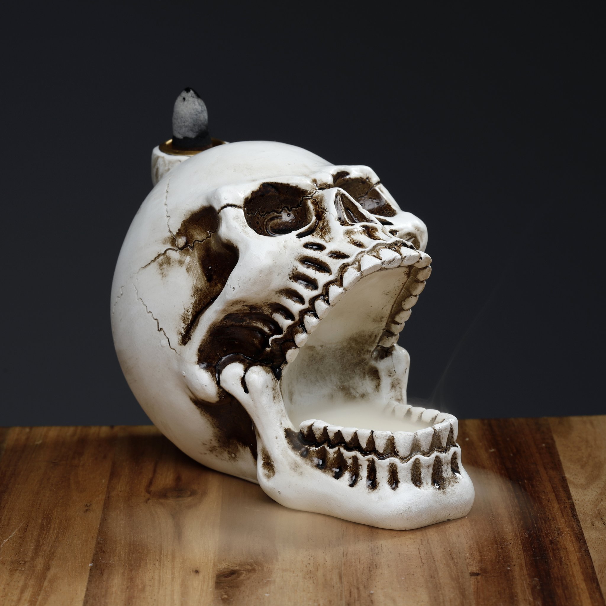 Skull incense holder with rising smoke in the dark