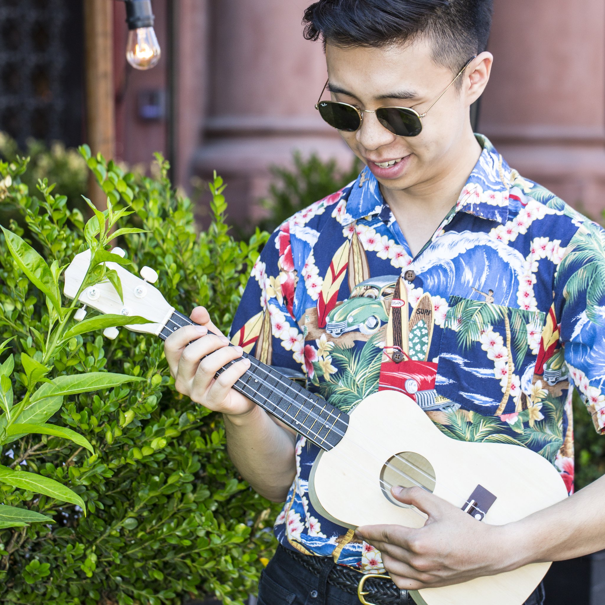 Mann mit Sonnenbrille stimmt die Ukulele aus dem Bausatz