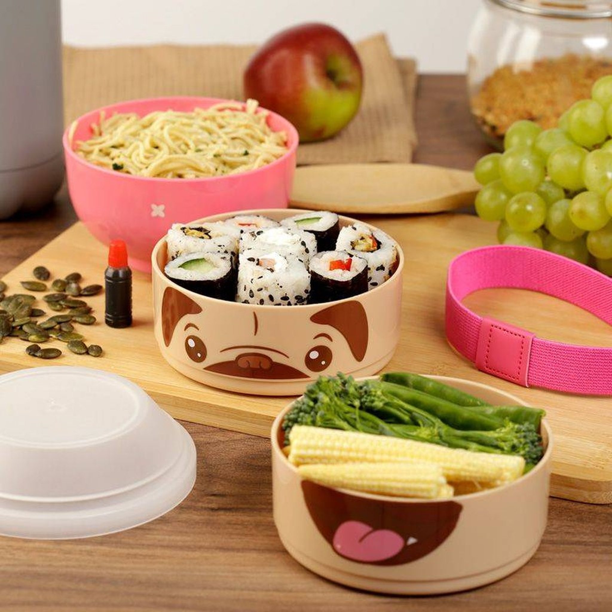 Mops-Bentobox gefuellt auf einem Holztisch mit Obst und Gemuese