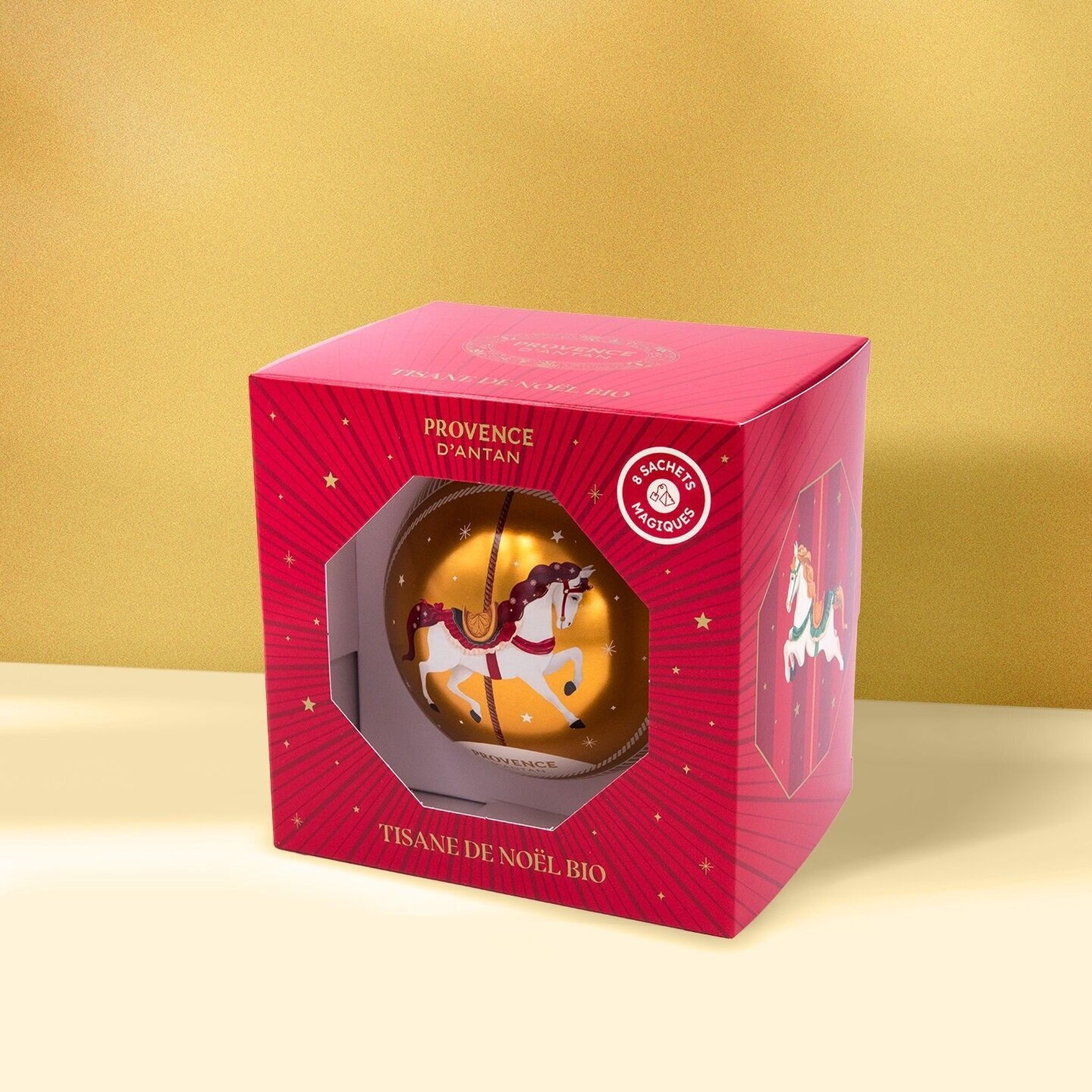 Geschenkkarton einer Kugel vor goldenem Hintergrund mit der Aufschrift Tisane de Noël bio