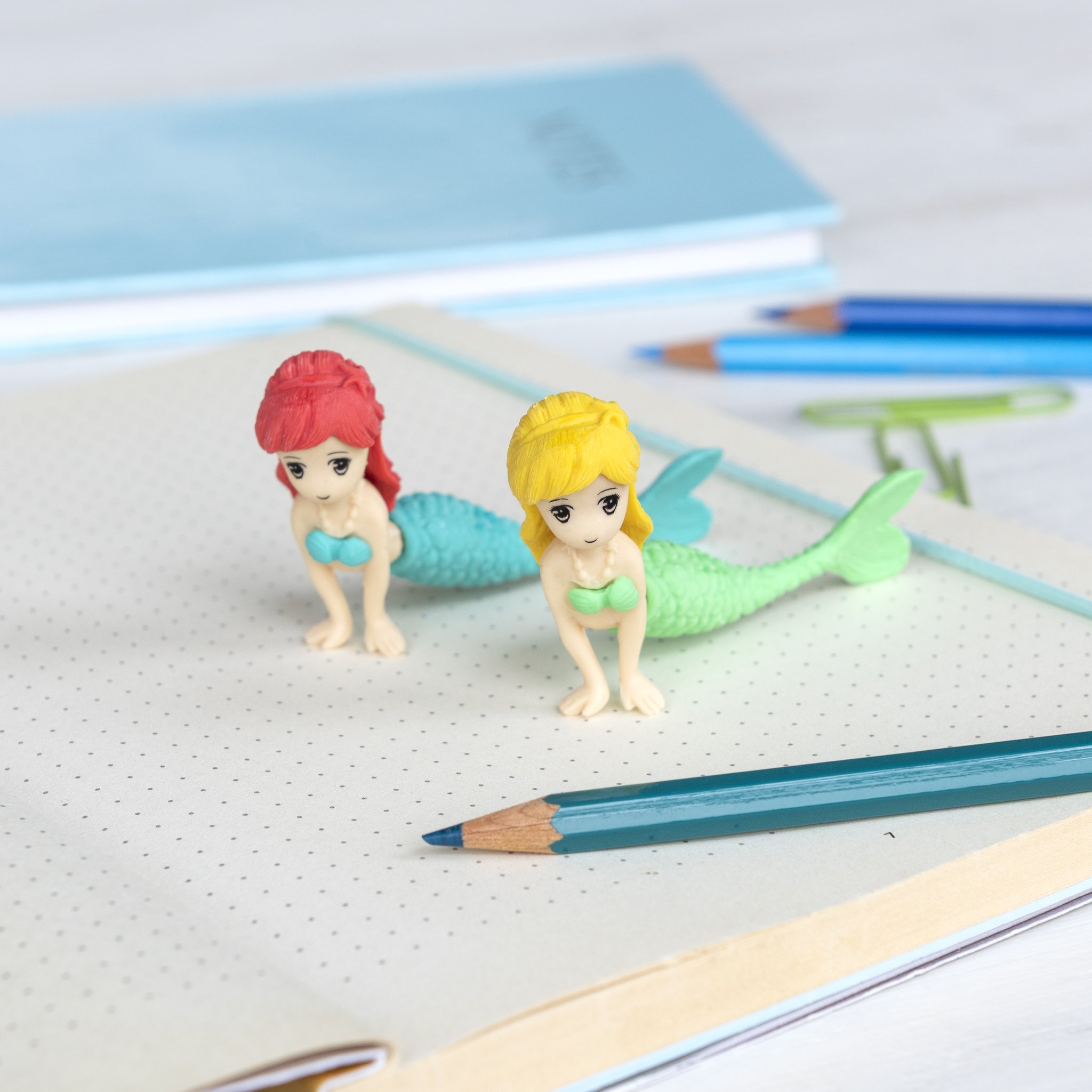 Set gomme sirena su un quaderno tra matite blu