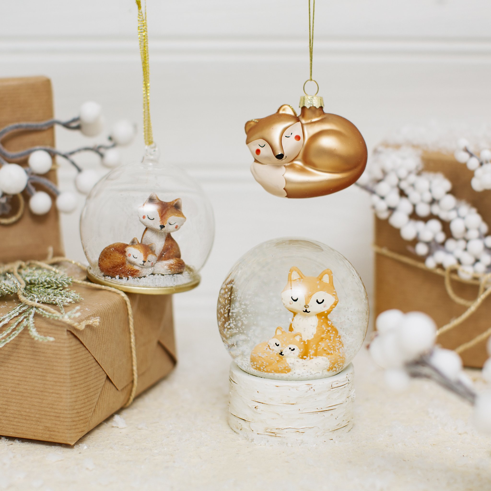 Fuchs Weihnachtsbaumschmuck hängend neben Fuchs-Schneekugeln und Geschenken