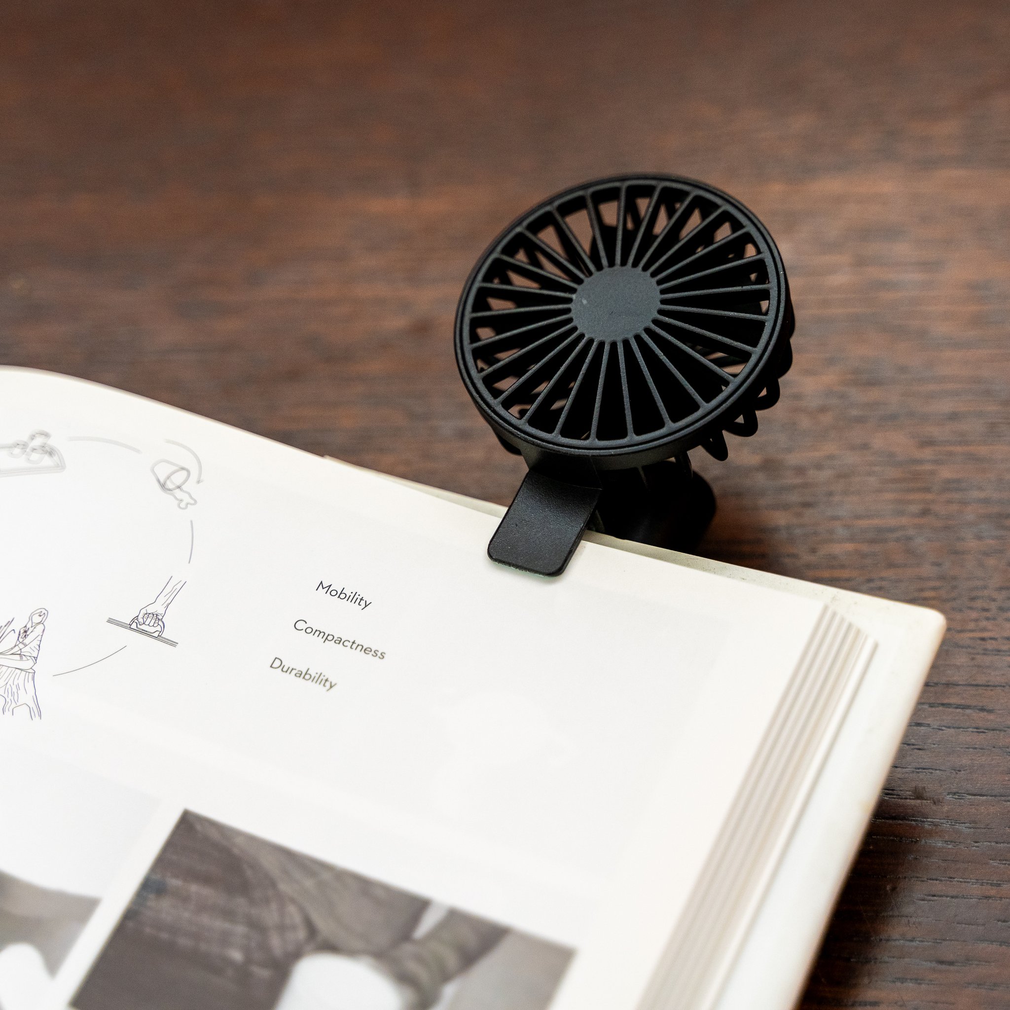Wiederaufladbarer Buchventilator klemmt an einem aufgeschlagenen Buch