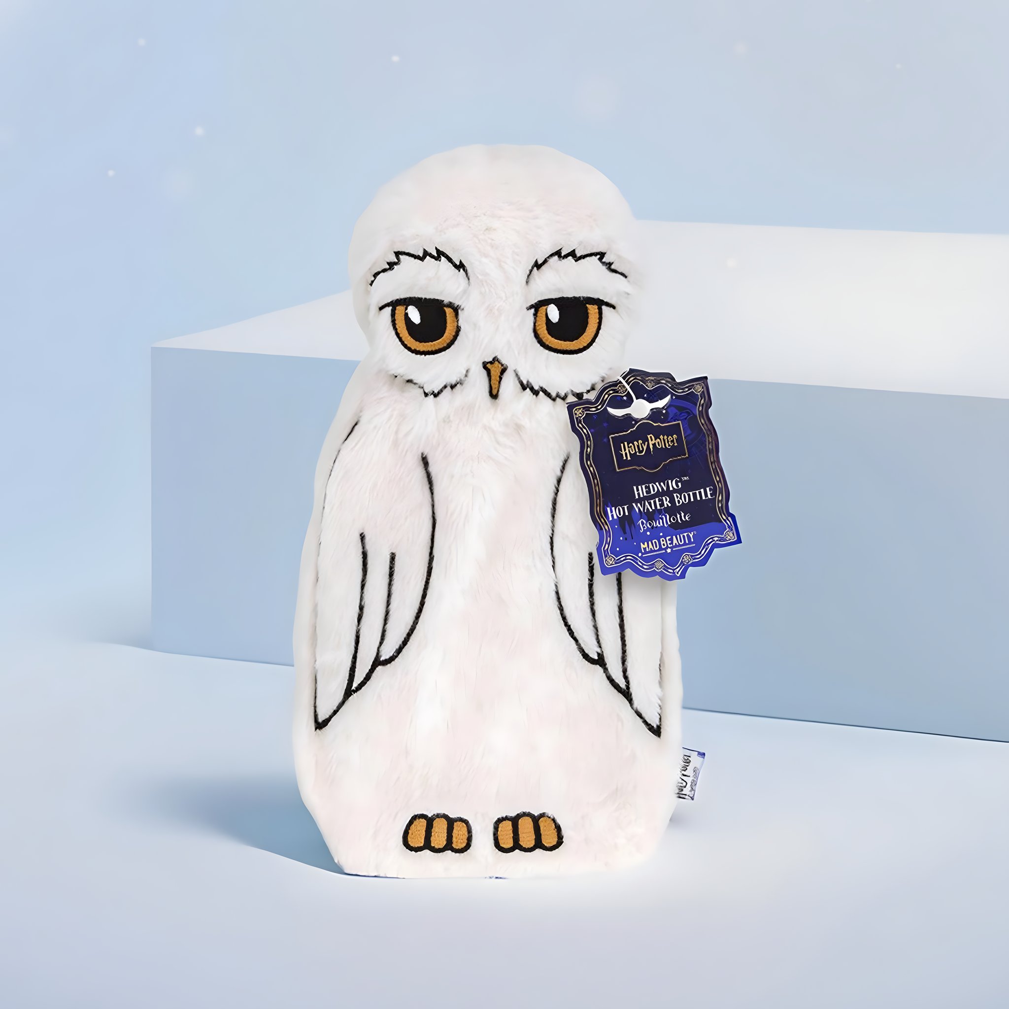 Bouillotte Hedwige en peluche blanche avec étiquette Harry Potter sur fond bleu clair