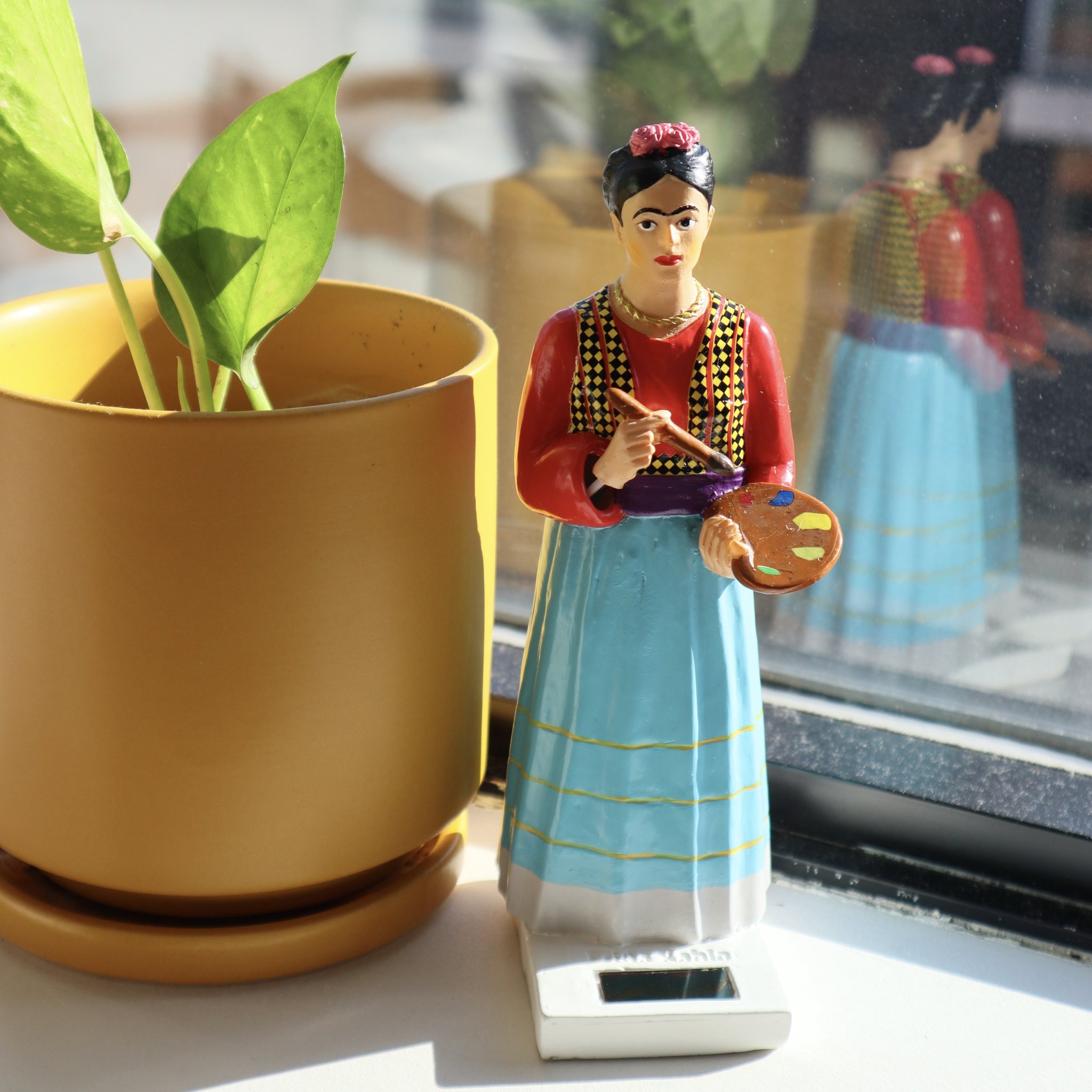 Solar-Figur Frida Kahlo neben einer Pflanze am Fenster