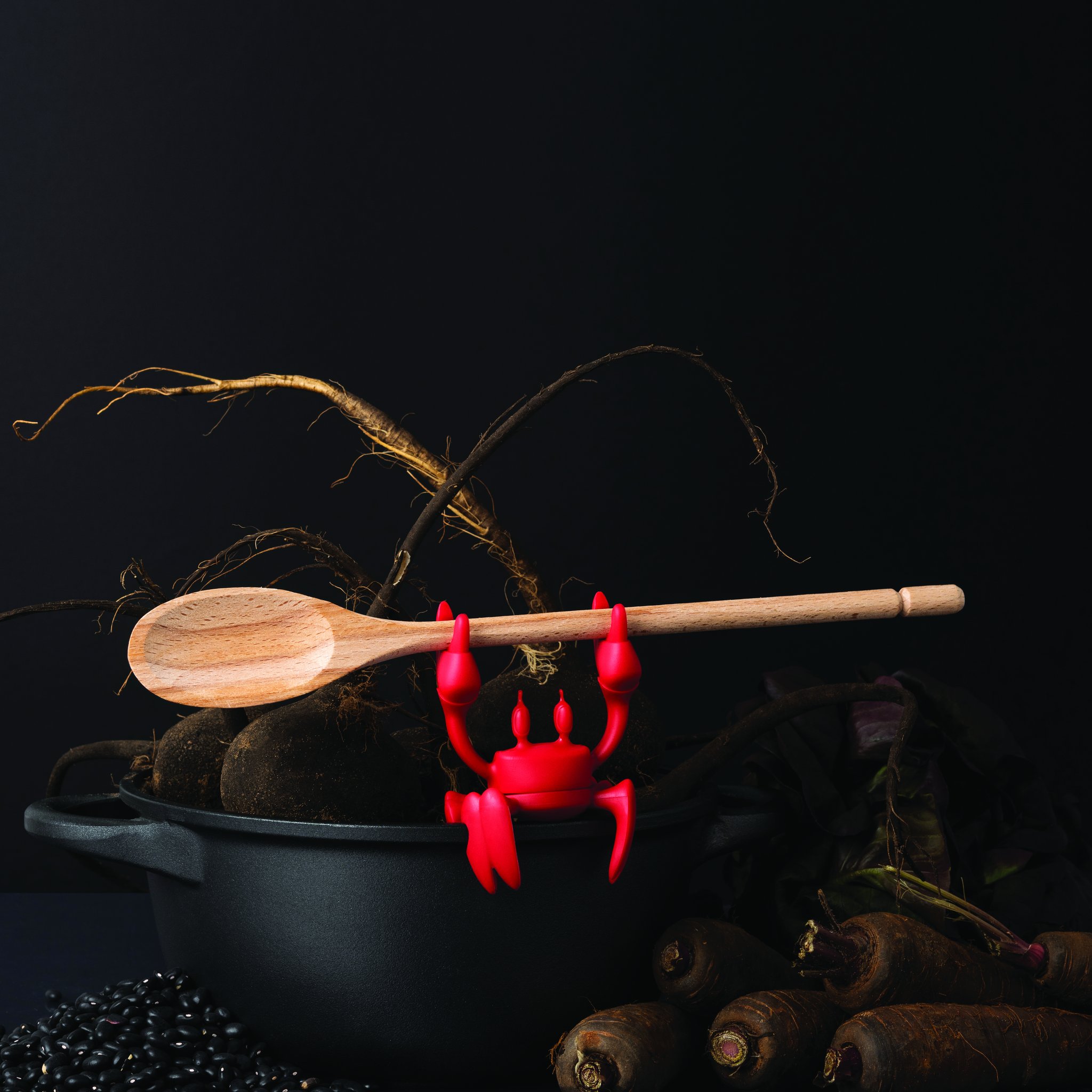 Wooden spoon held above a cooking pot by the red crab