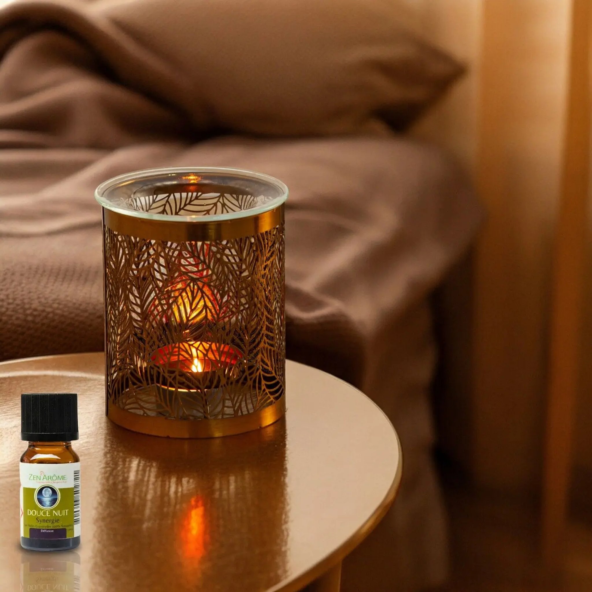Tealight glowing through the leaf pattern of the oil burner on a bedside table