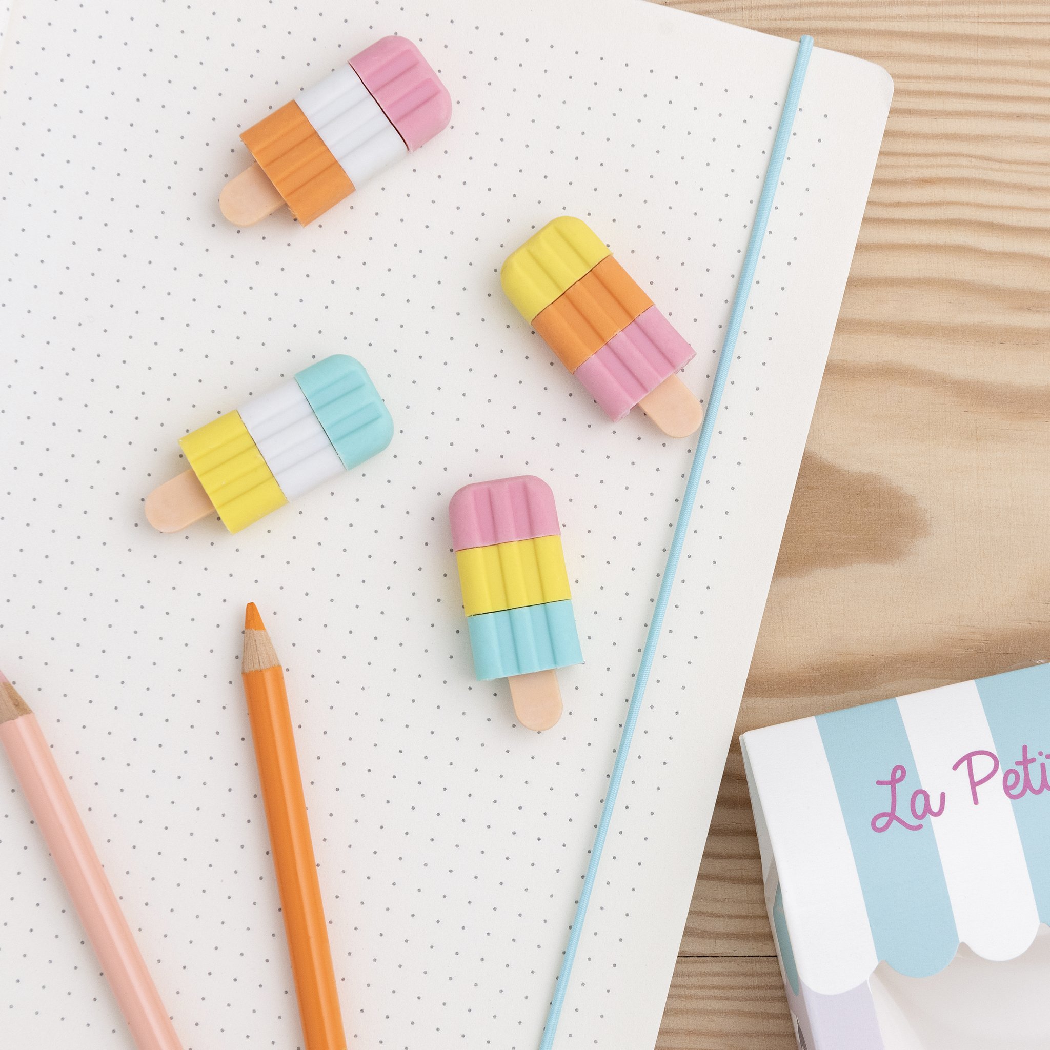 Ice lolly erasers on a dotted notebook with pencils and ice cream parlour box