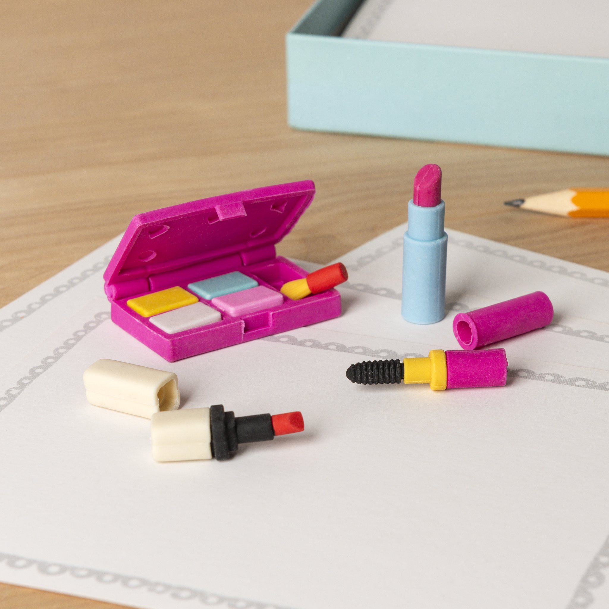 Makeup erasers: palette, lipsticks and mascara on a sheet of paper, box behind