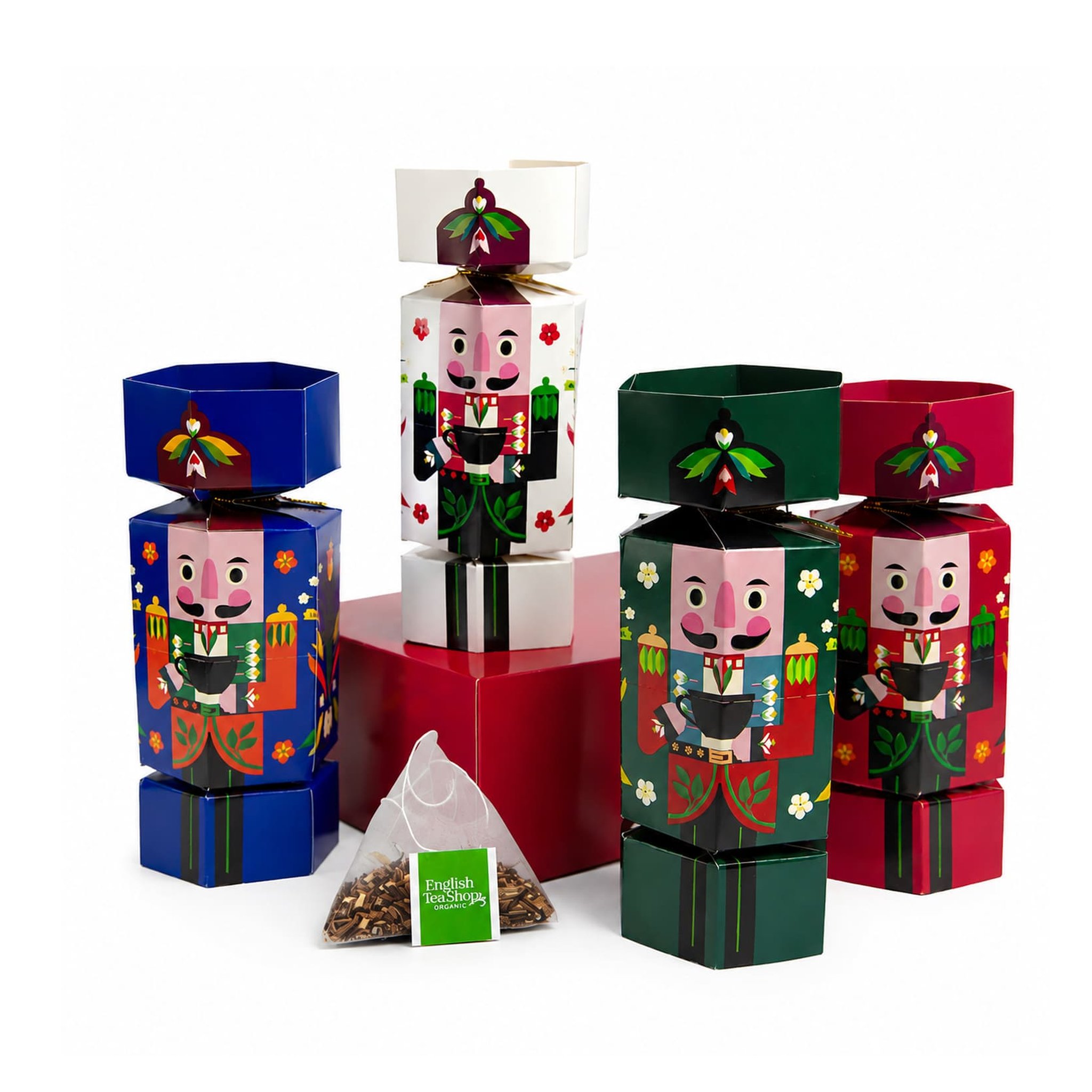 Quatre étuis casse-noisette bleu, blanc, vert et rouge debout, devant un sachet pyramide