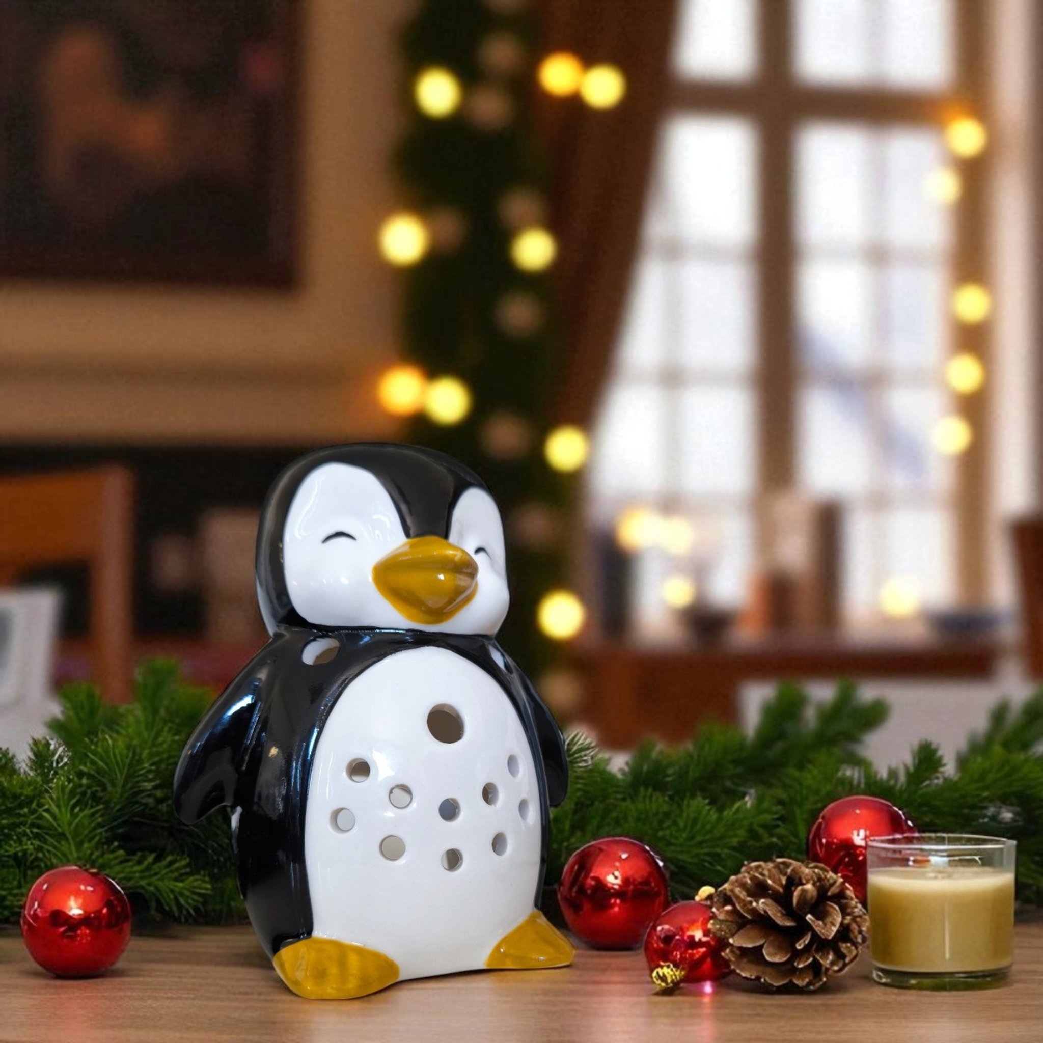Pinguin-Duftlampe in weihnachtlicher Deko mit Tannenzweigen und Kugeln