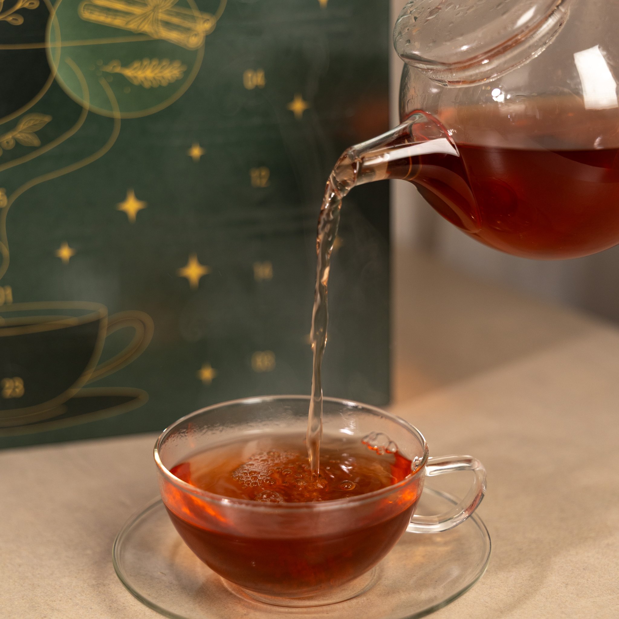 Thé versé d'une théière en verre dans une tasse devant le calendrier de l'Avent