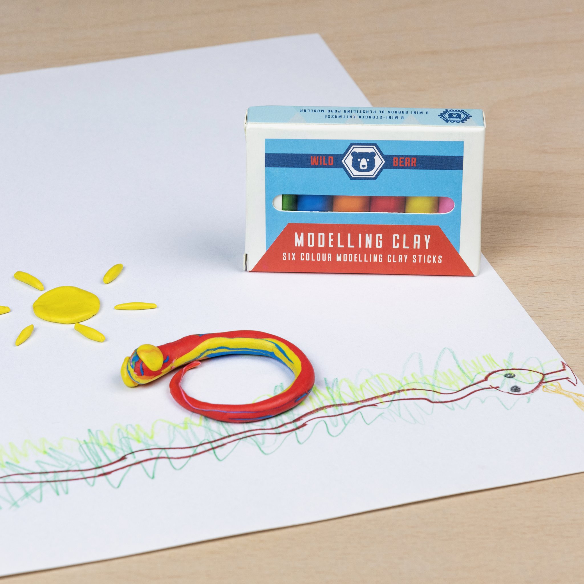 Wild Bear modelling clay: sun and rings made of clay on a drawing sheet, box behind