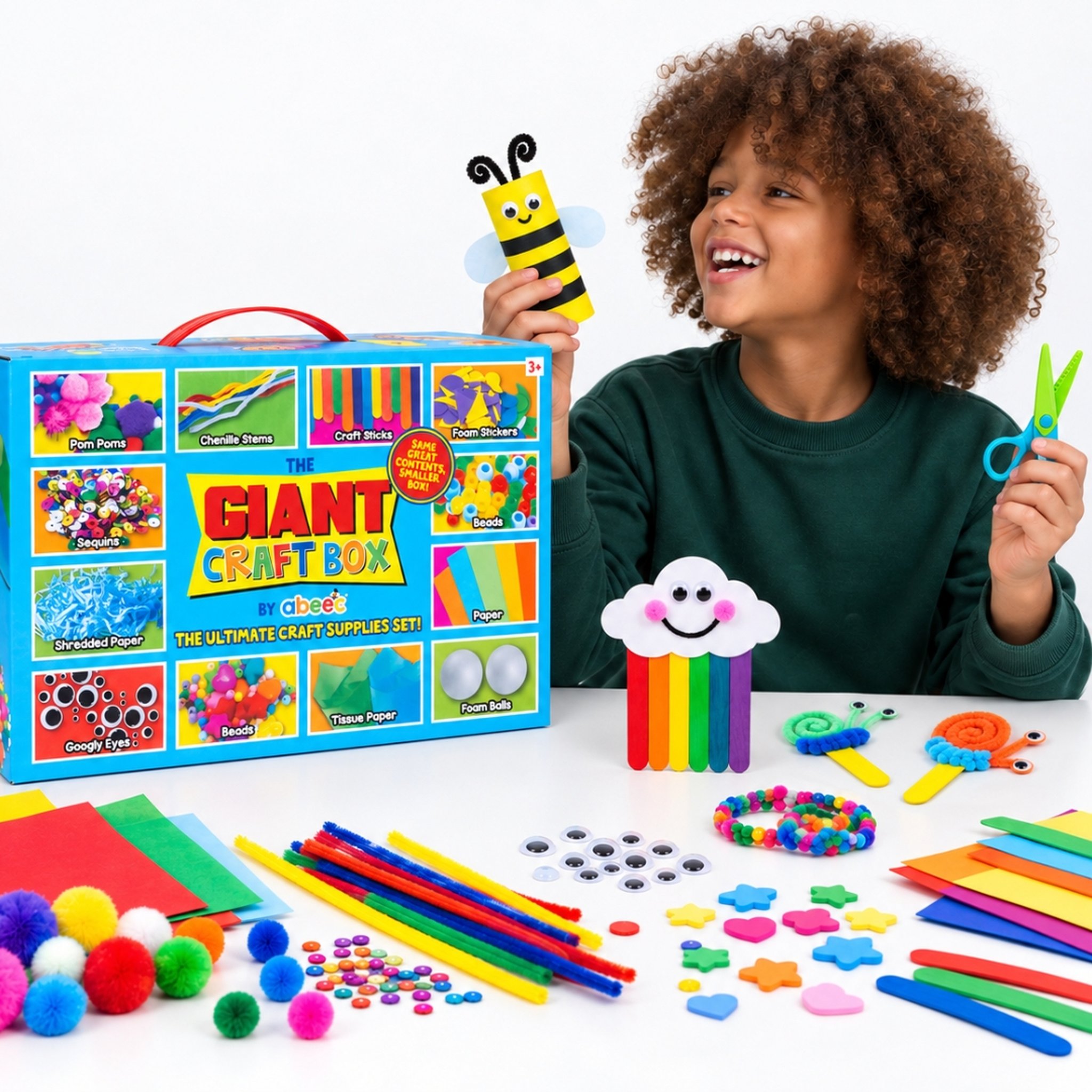 Garçon brandissant une abeille bricolée et des ciseaux, avec la boîte de bricolage géante sur la table