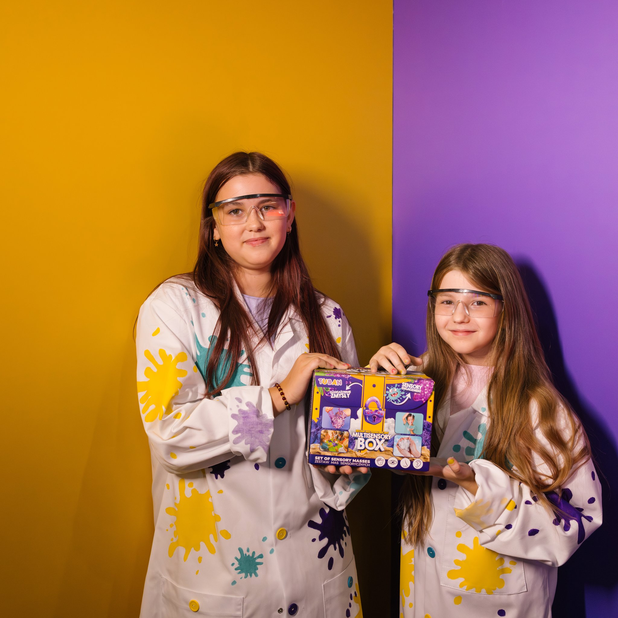 Due ragazze in camice da laboratorio presentano la Multisensory Box di Tuban