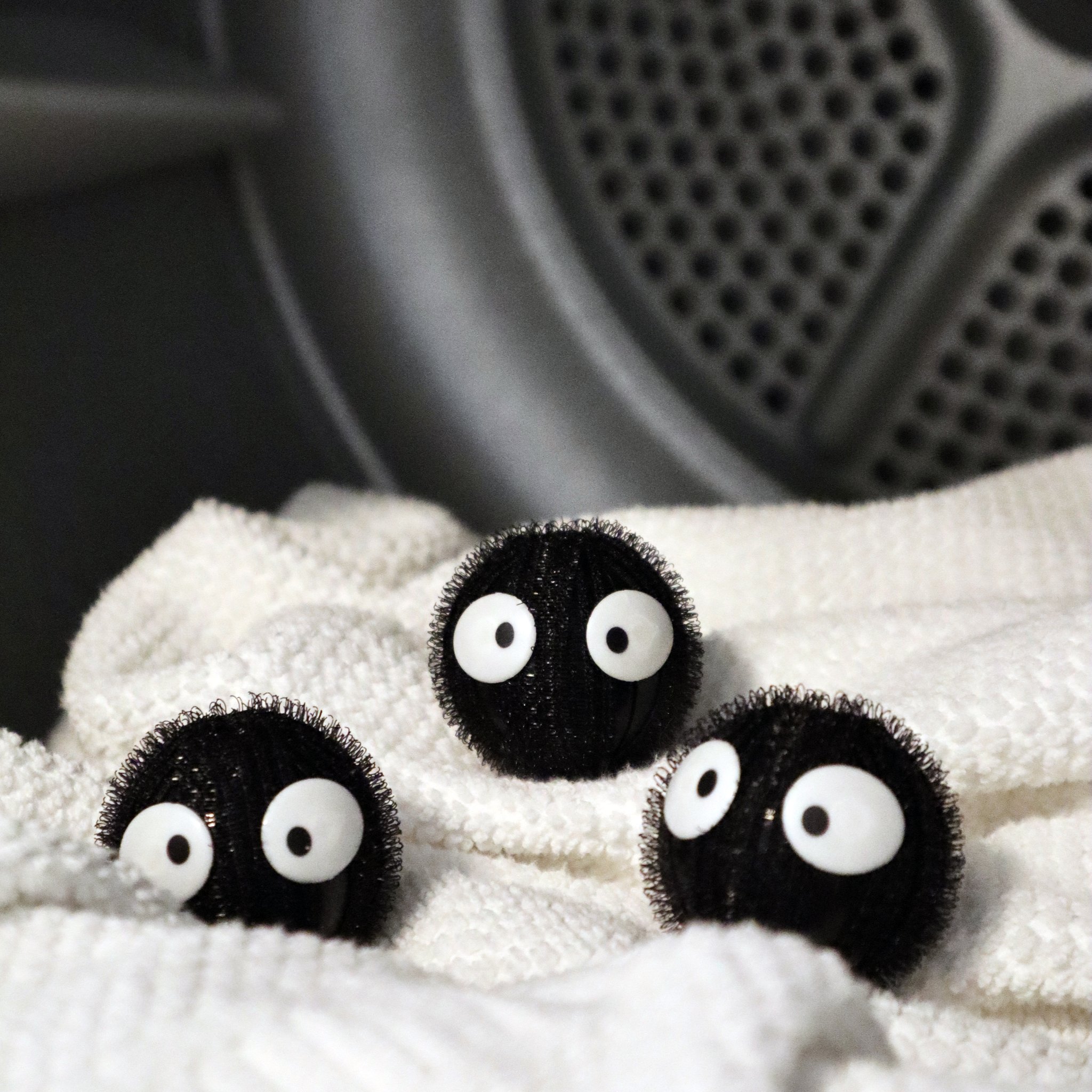 Drei Wäsche-Buddies mit Kulleraugen auf einem weissen Handtuch im Trockner