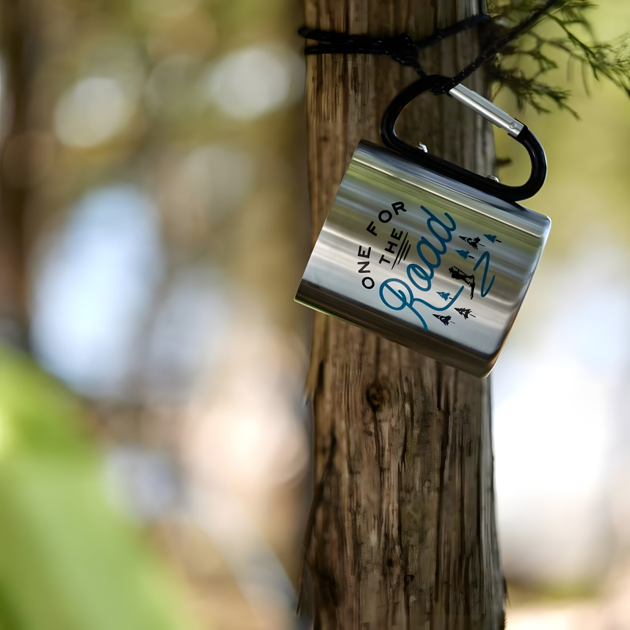 Die Karabinertasse hängt mit ihrem Karabiner an einem Baumstamm im Wald, Hintergrund weich unscharf