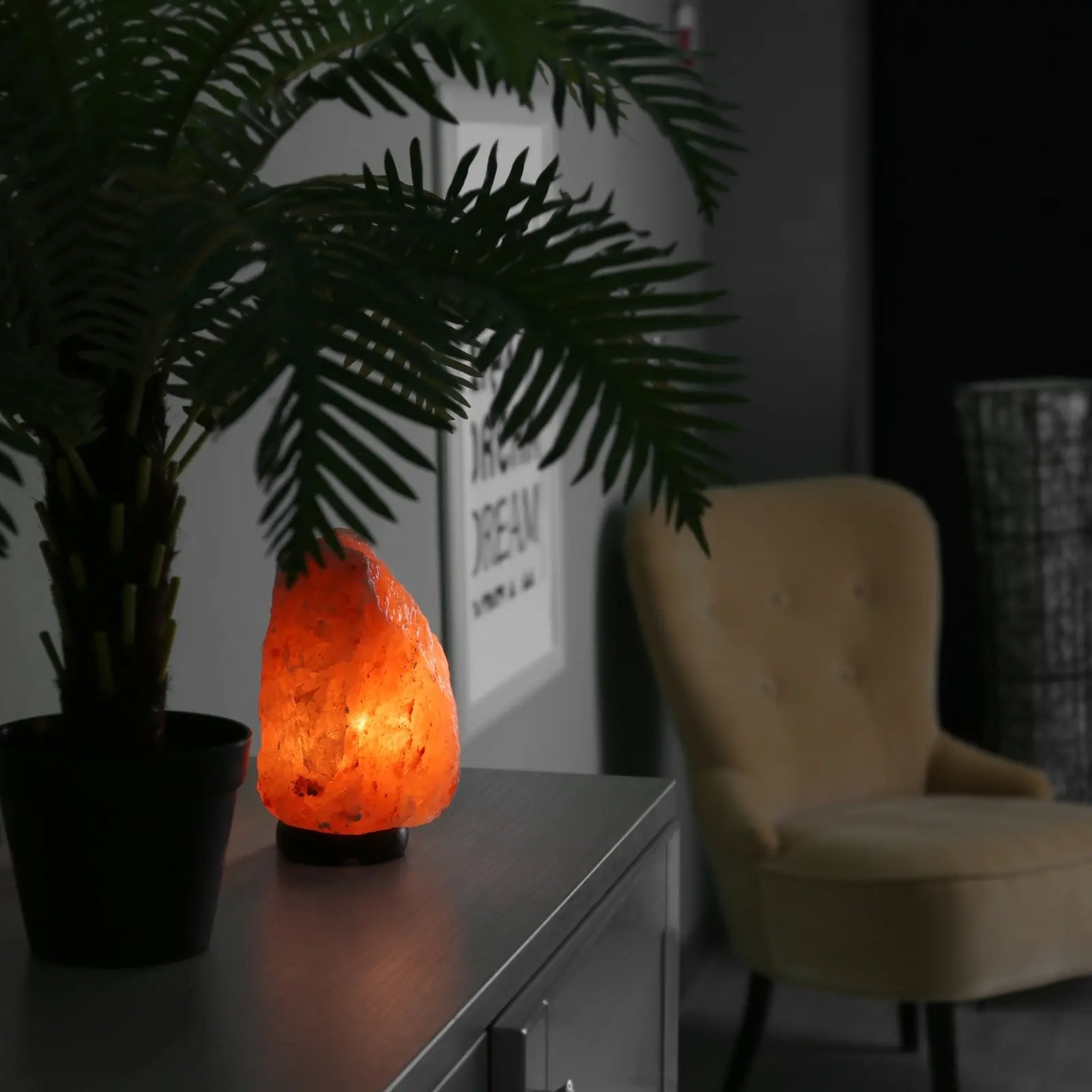 Glowing Himalayan salt lamp with warm orange light on a chest of drawers