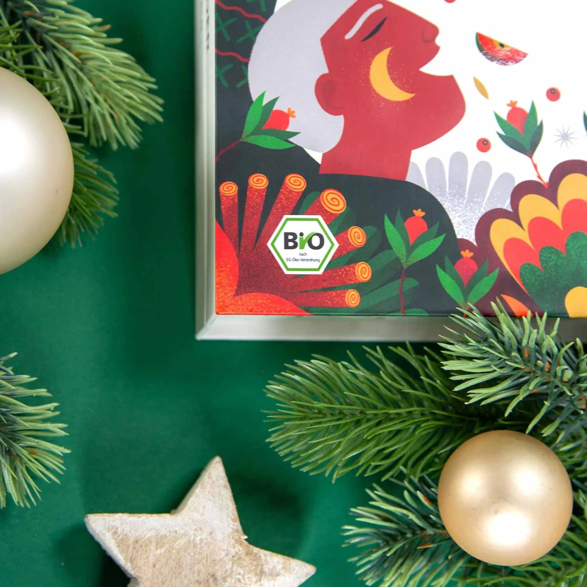 Close-up of the tea advent calendar with organic label among fir branches, baubles and a decorative star