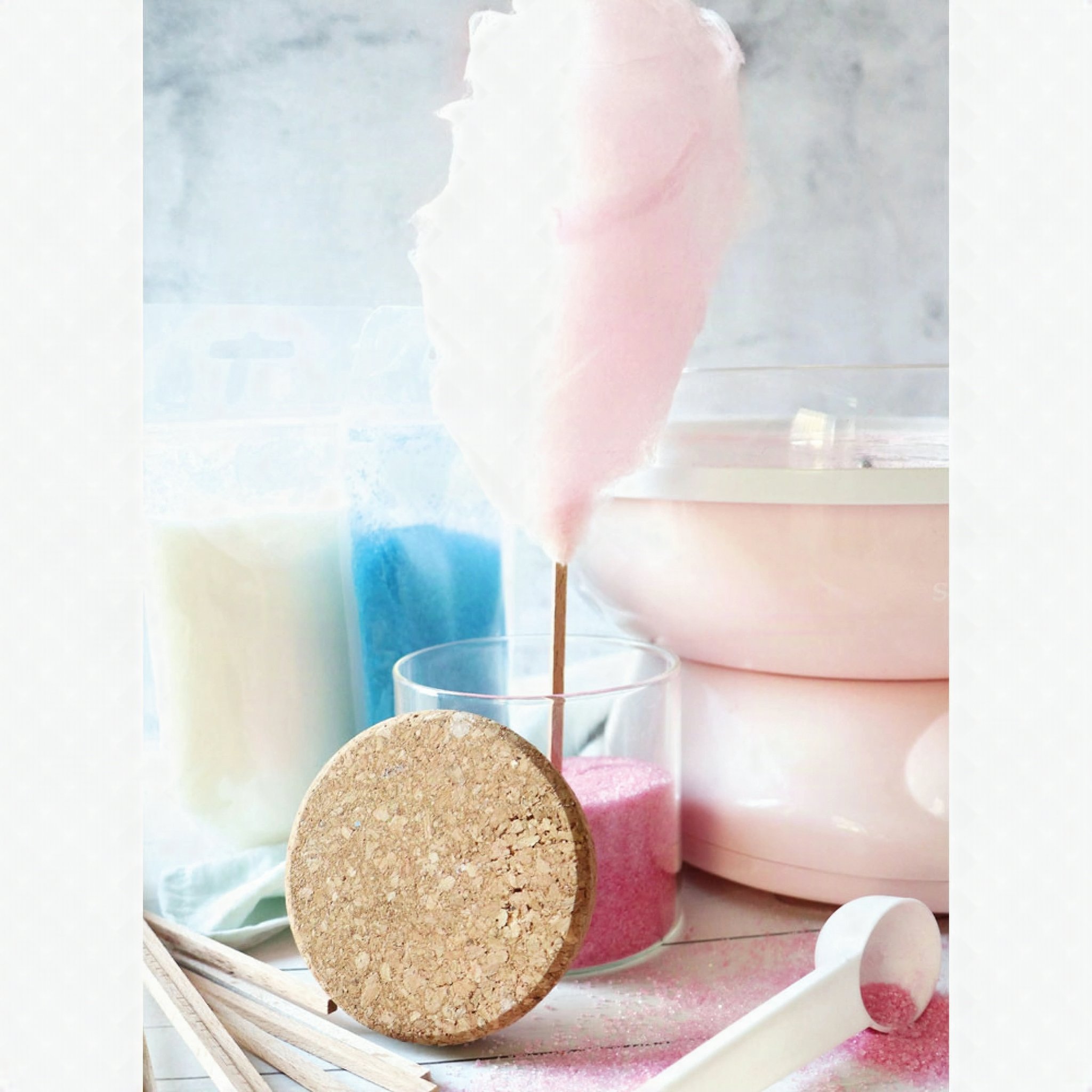 Rosa Zuckerwatte am Stäbchen neben Zuckerwattemaschine