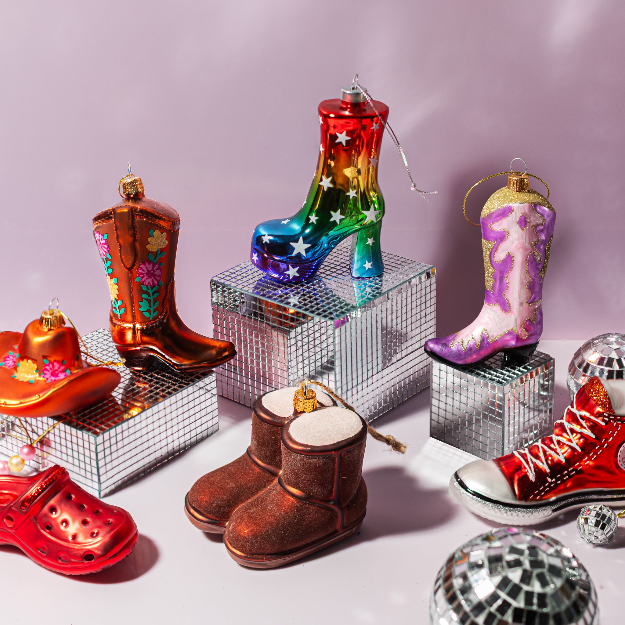 Zoccolo rosso in vetro tra decorazioni a forma di stivali e scarpe su sfondo rosa