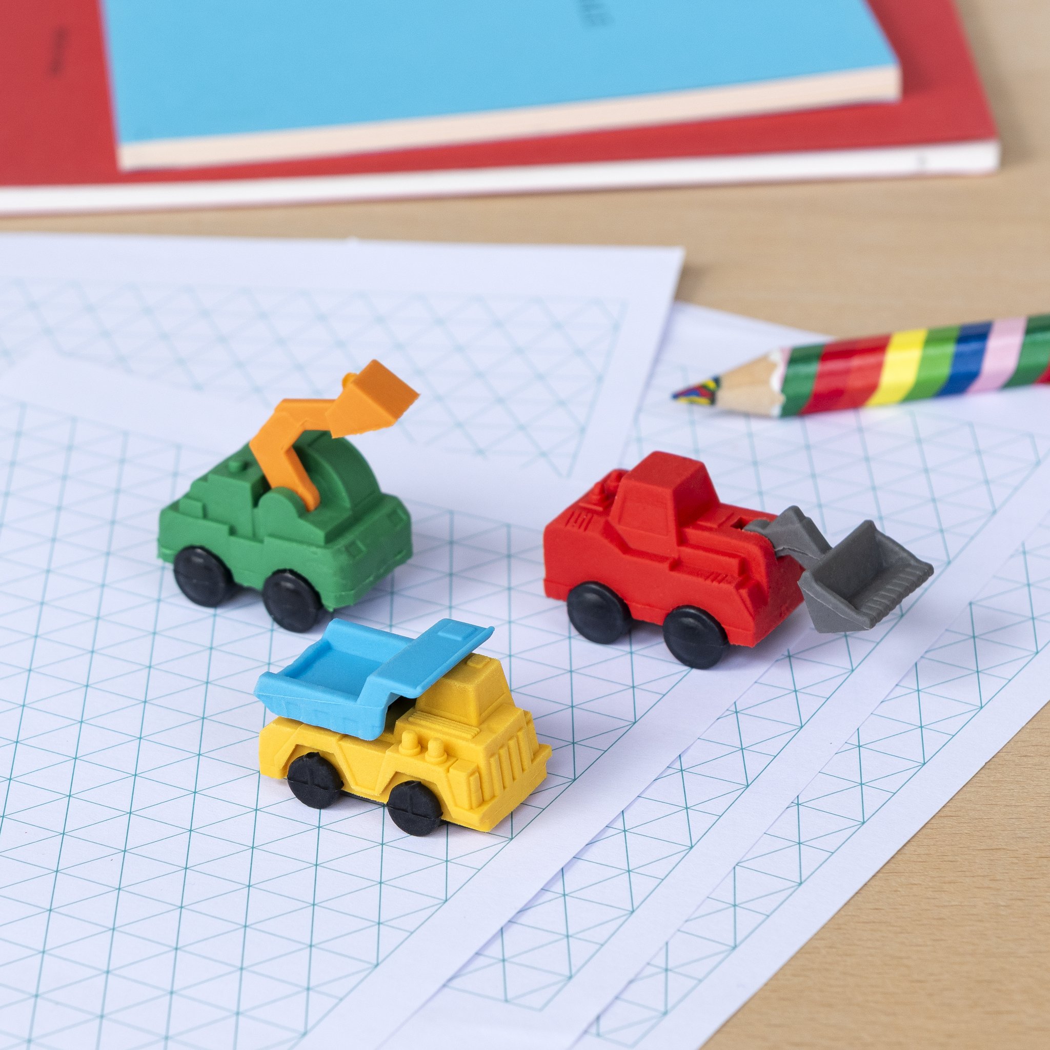 Construction vehicle erasers: digger, tipper and tractor on squared paper with pencil