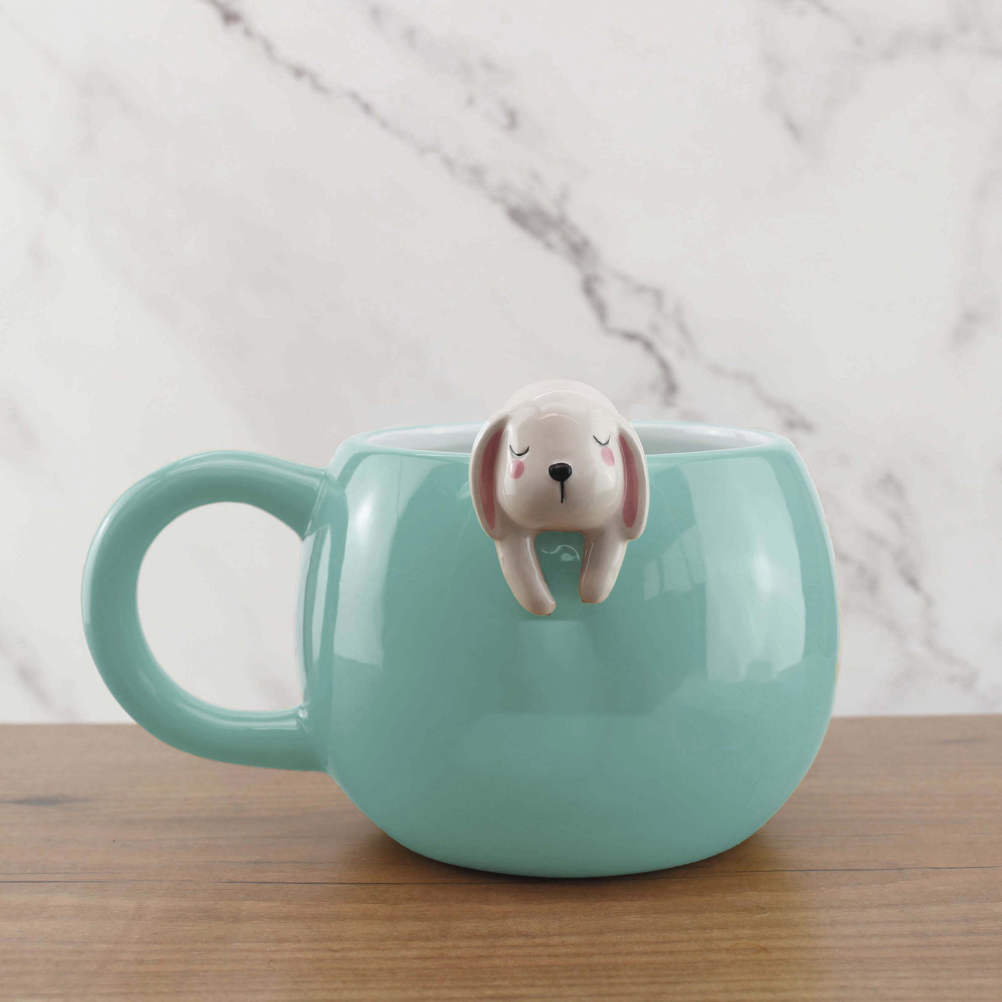 Mintgrüner Kaffeebecher mit kleiner Hasenfigur am Tassenrand
