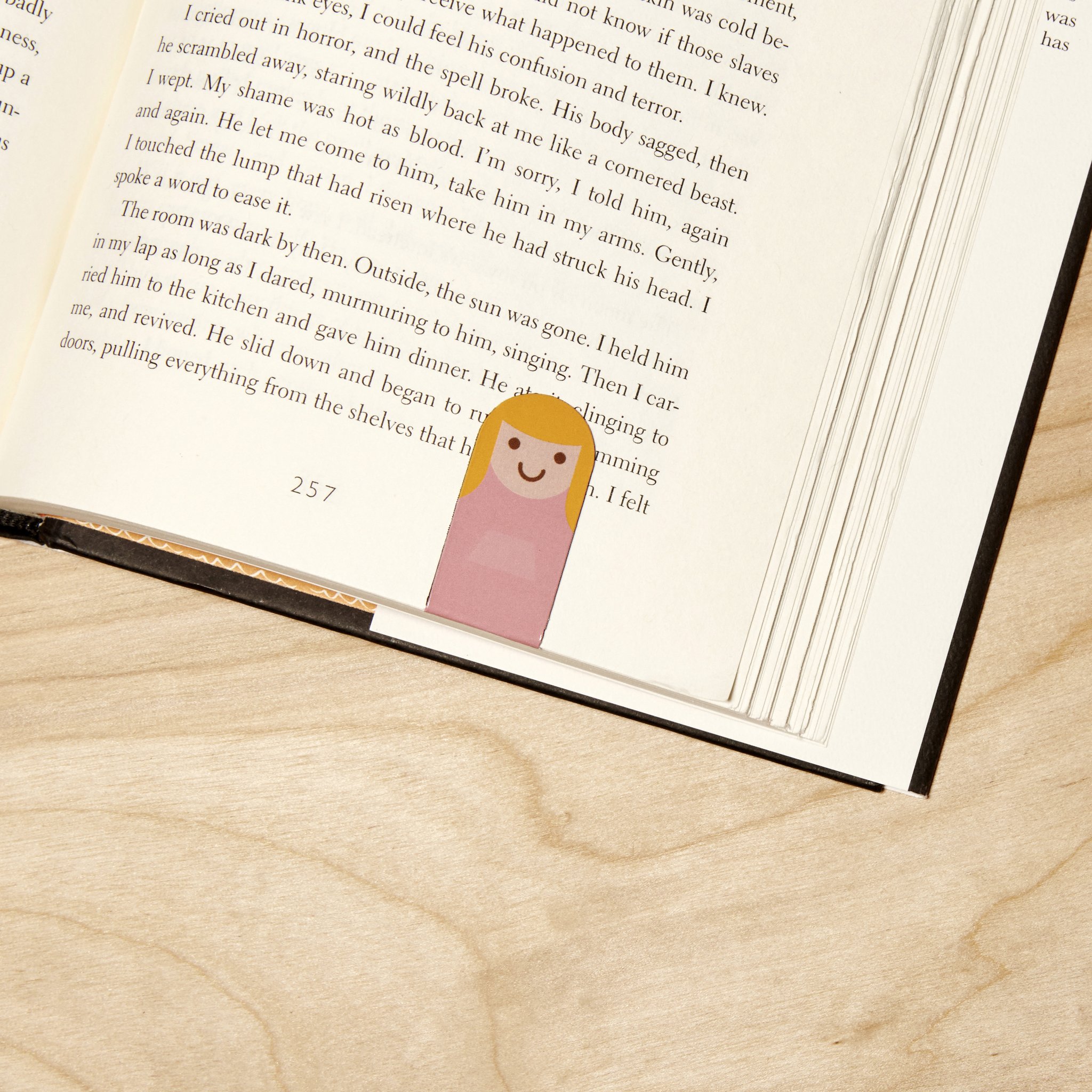 Bookmark with pink figure clipped to the top of the page