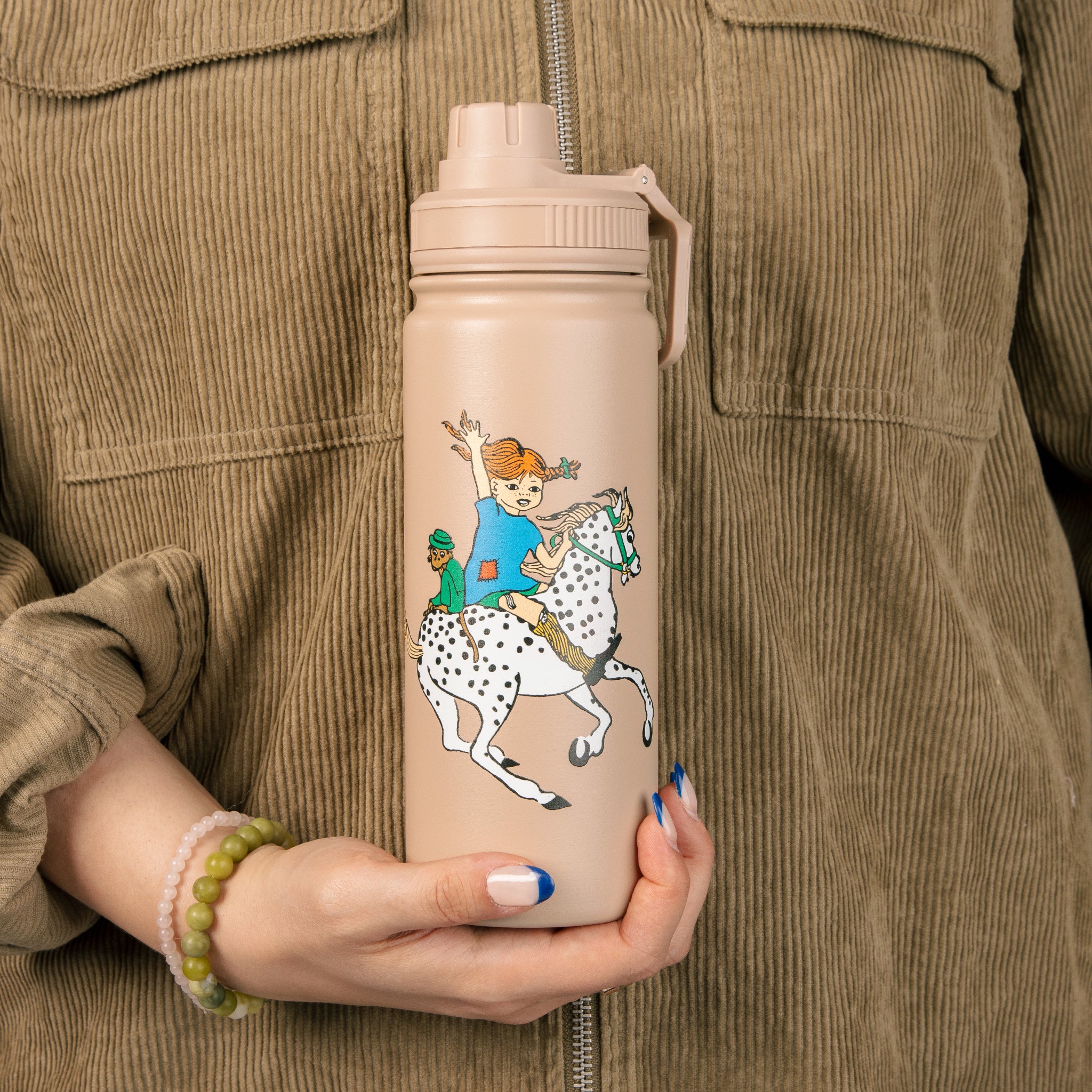 Pippi Longstocking thermal bottle held in one hand in front of a corduroy jacket
