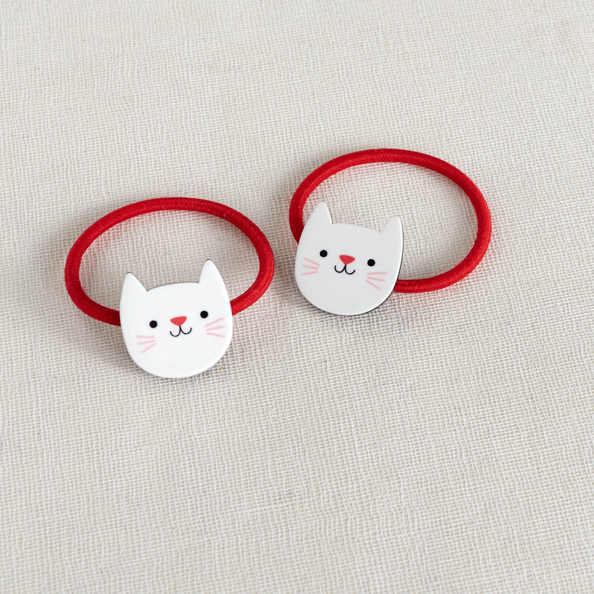 Cookie the Cat hair ties: two red ties with white cat head on linen