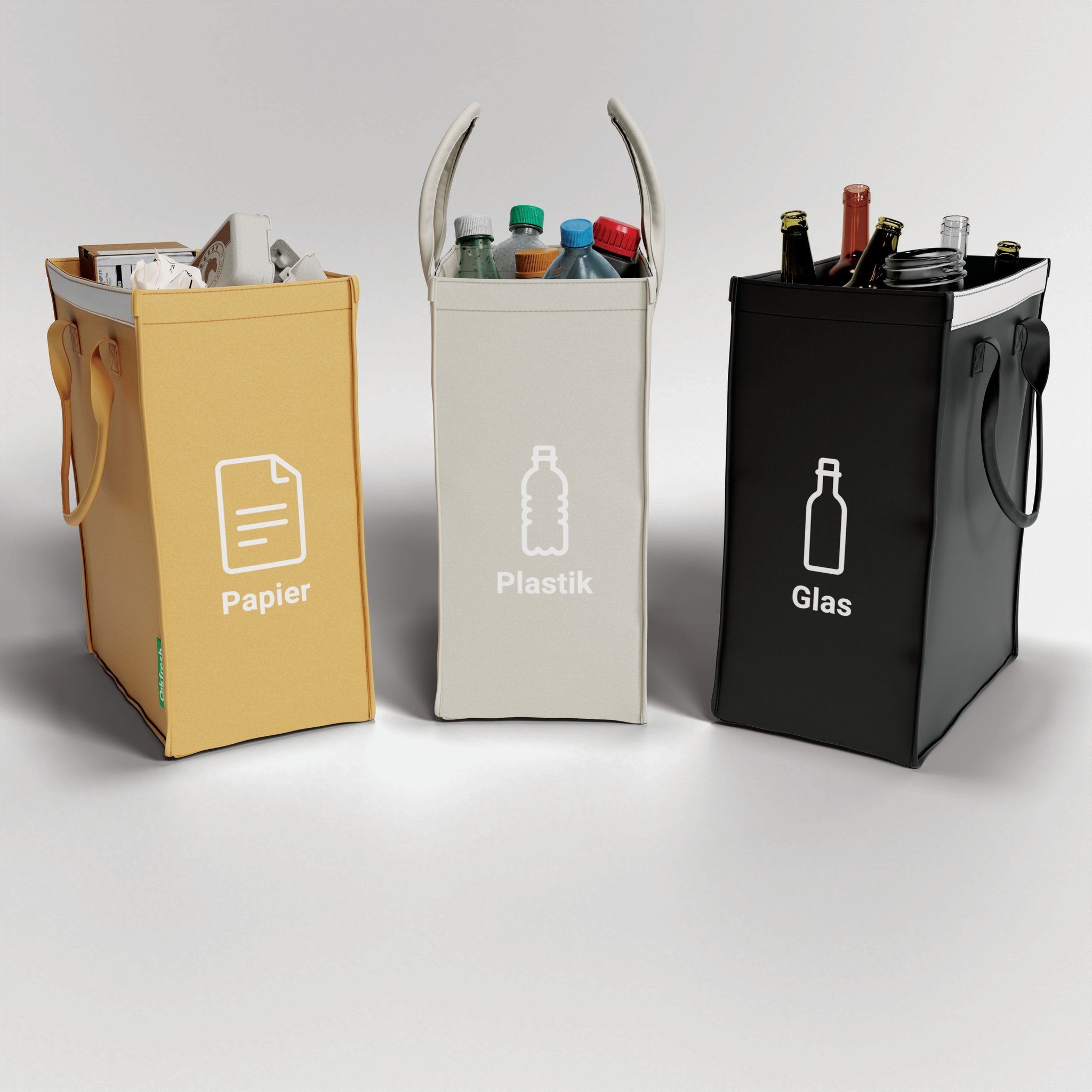 Tre sacche separate con manici, riempite di carta, bottiglie di plastica e vetro